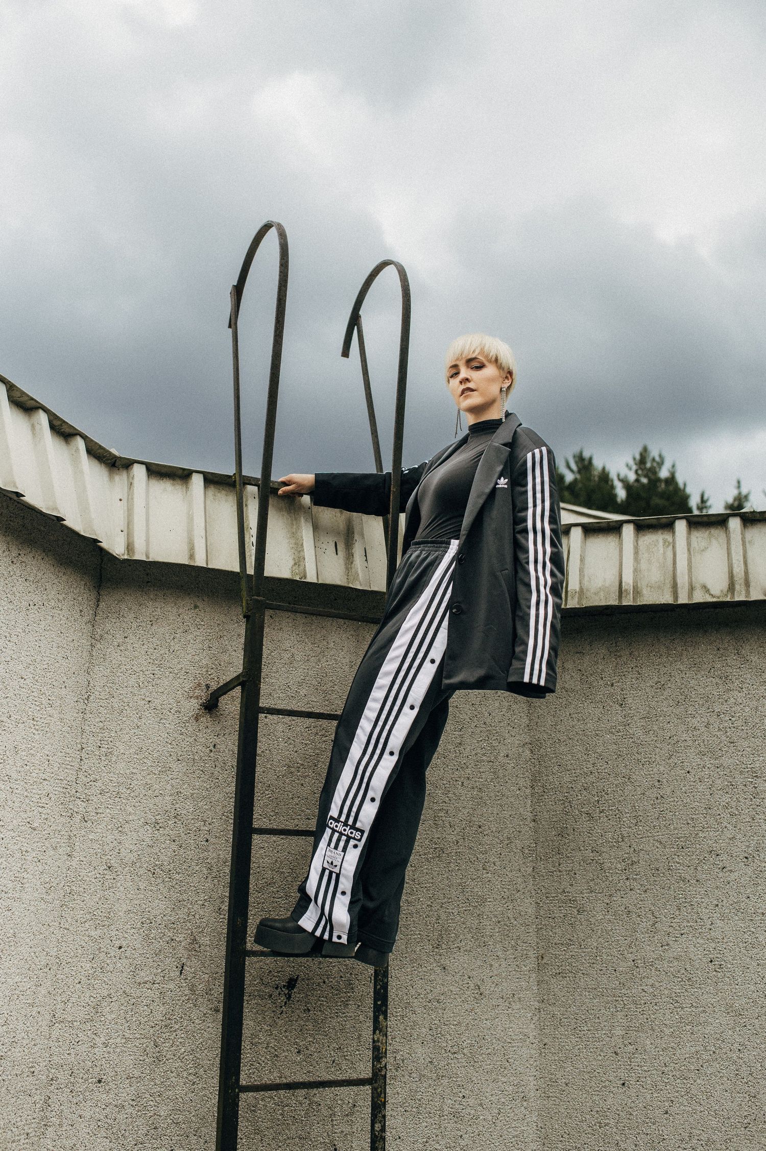 Athletic fashion shoot featuring Adidas sportswear against concrete walls and metal structures.