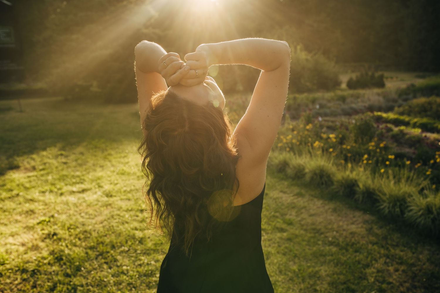 Silhouette figure in golden sunlight with arms raised against a natural outdoor backdrop.