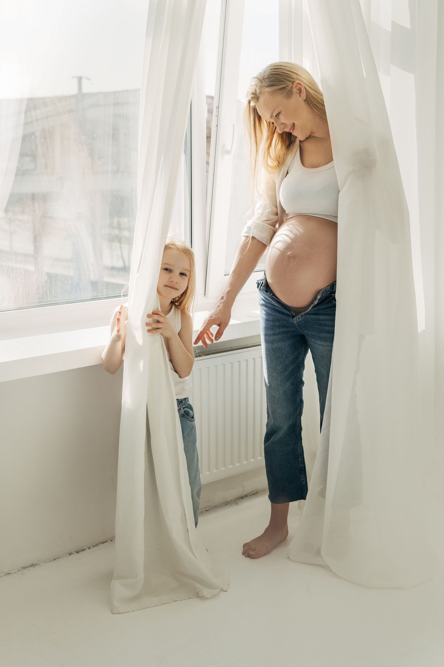 Series of playful photos showing small child peeking through white curtains.