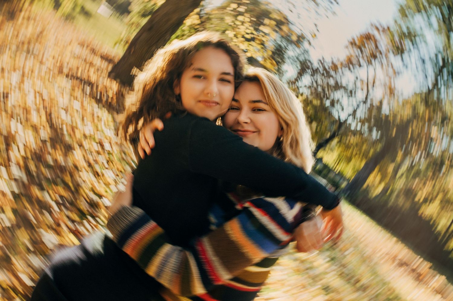 Autumn outdoor photoshoot with blurred golden leaves and warm lighting.