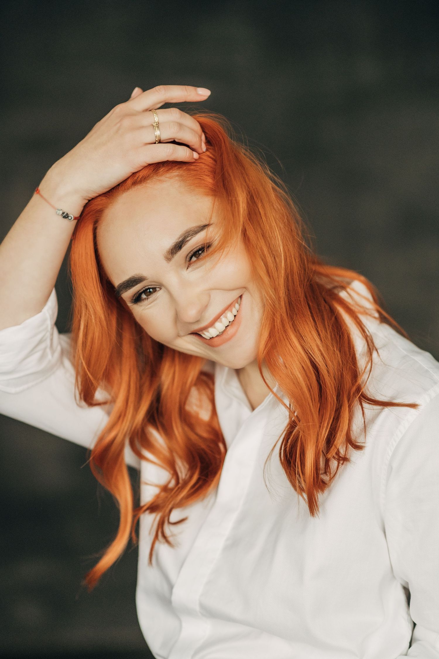 Vibrant portrait featuring bright orange hair against dark background.