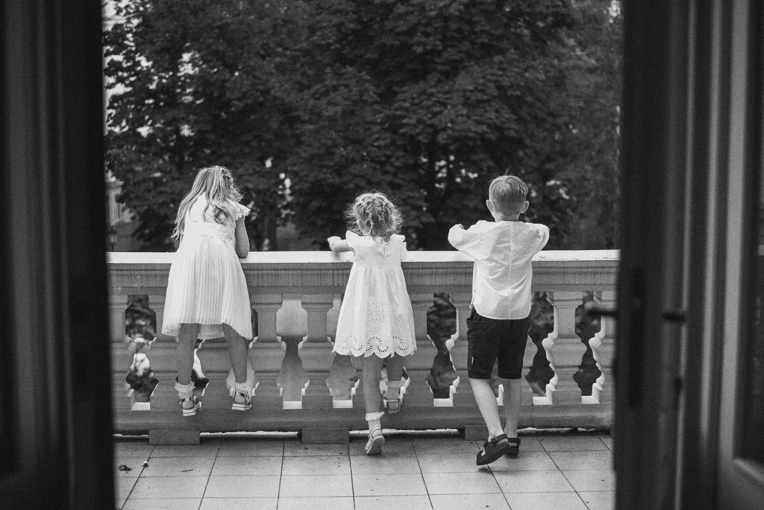 Black and white view of children playing through window frame.