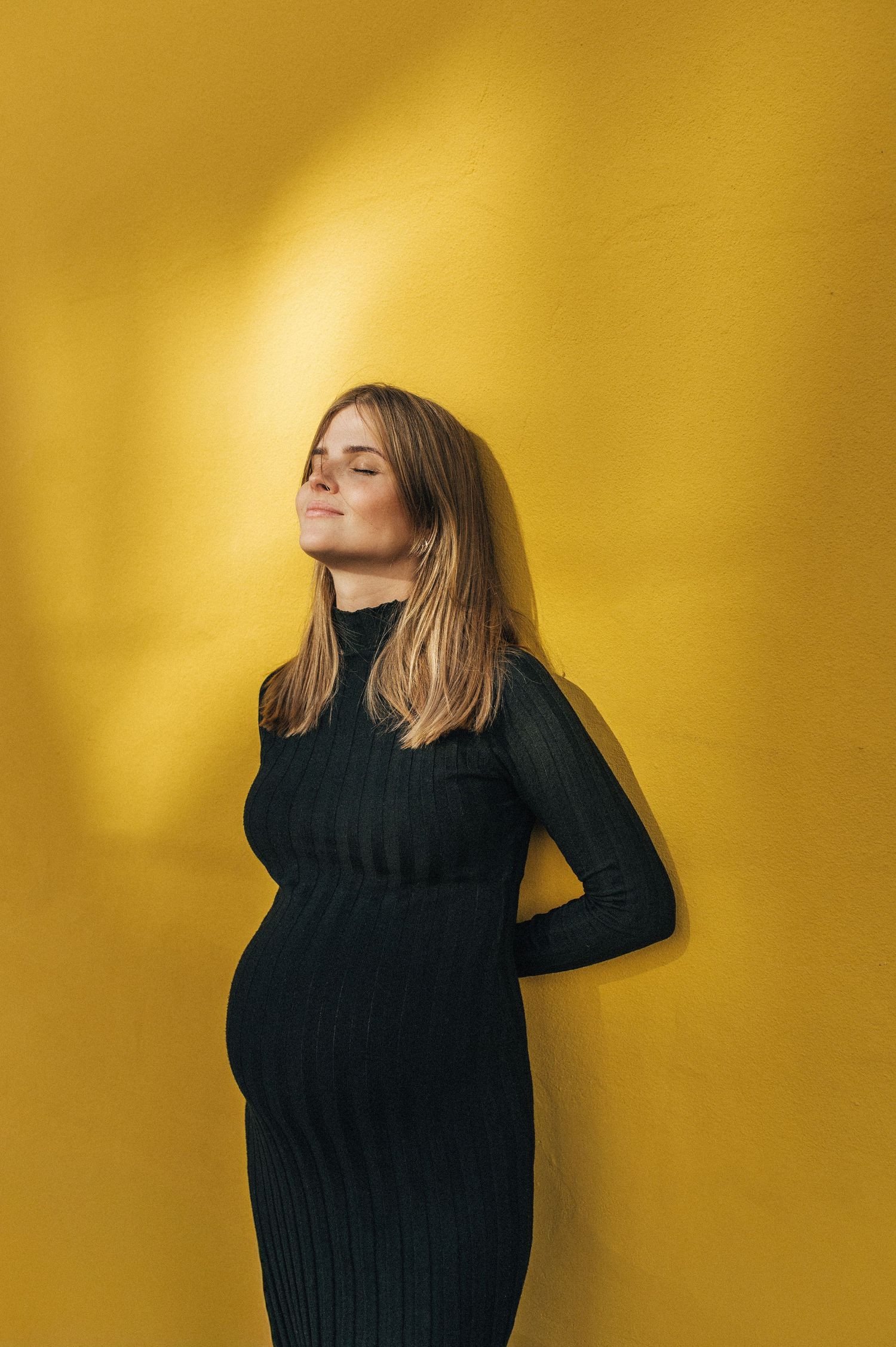 Artistic portrait series against vibrant yellow backdrop showing movement in black sweater.