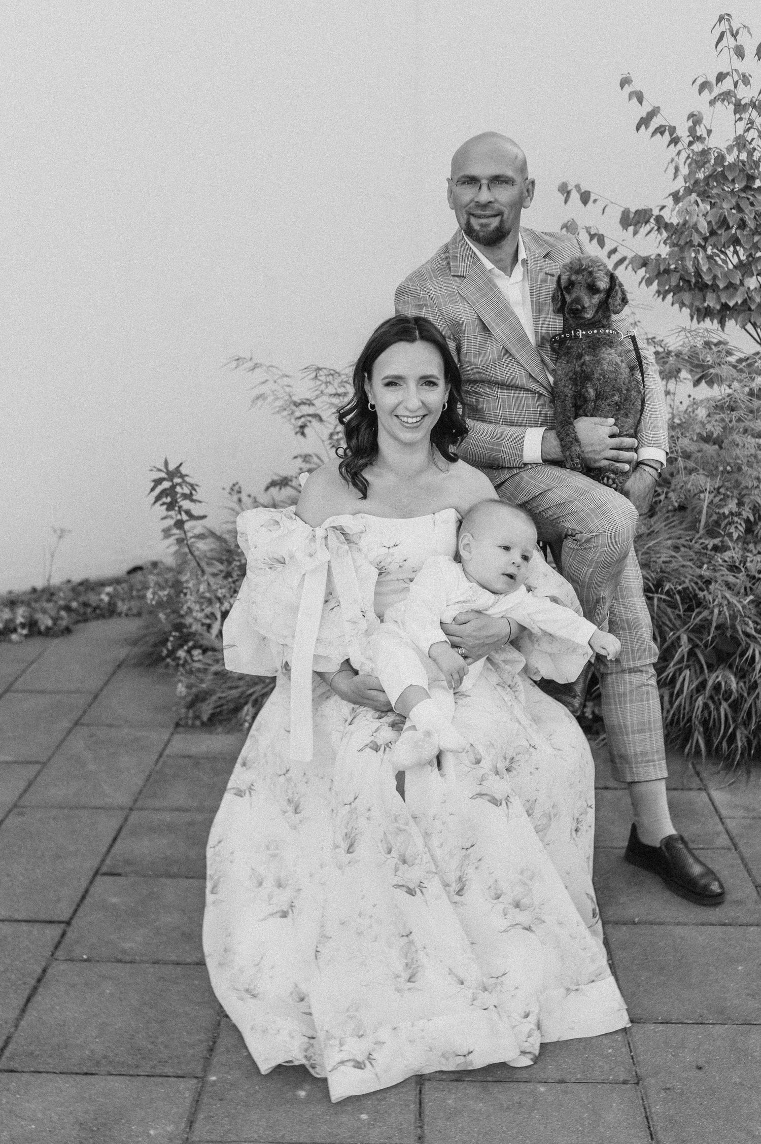 A series of black and white photos showing a family outdoors on a patio in matching white floral outfits.