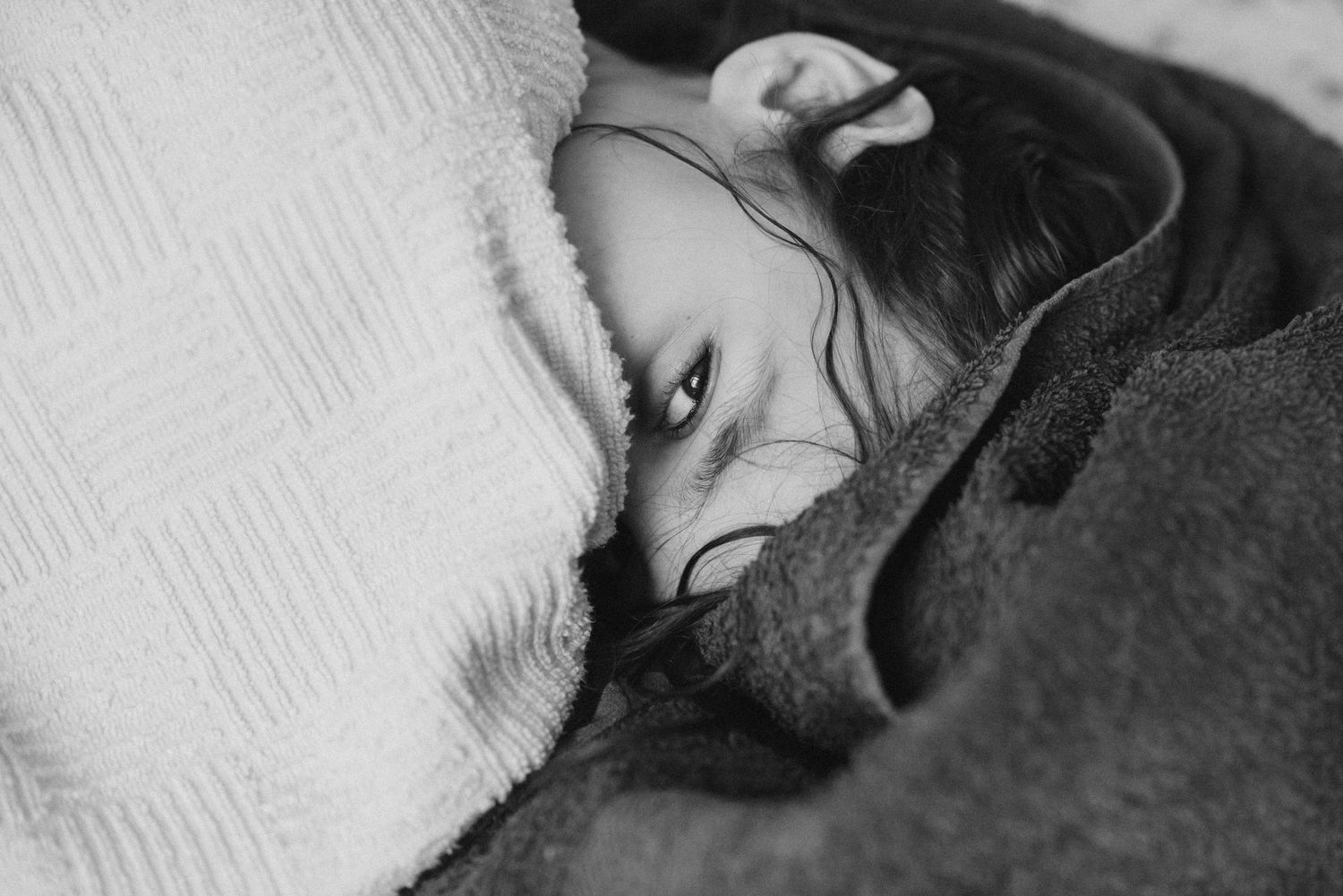 Black and white close-up of person sleeping peacefully on textured surface.