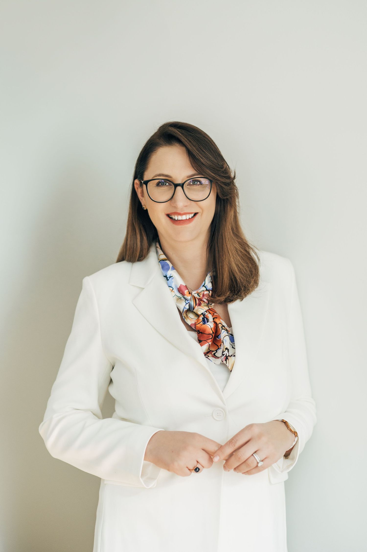 Professional headshot series showing someone in a white blazer and patterned scarf.