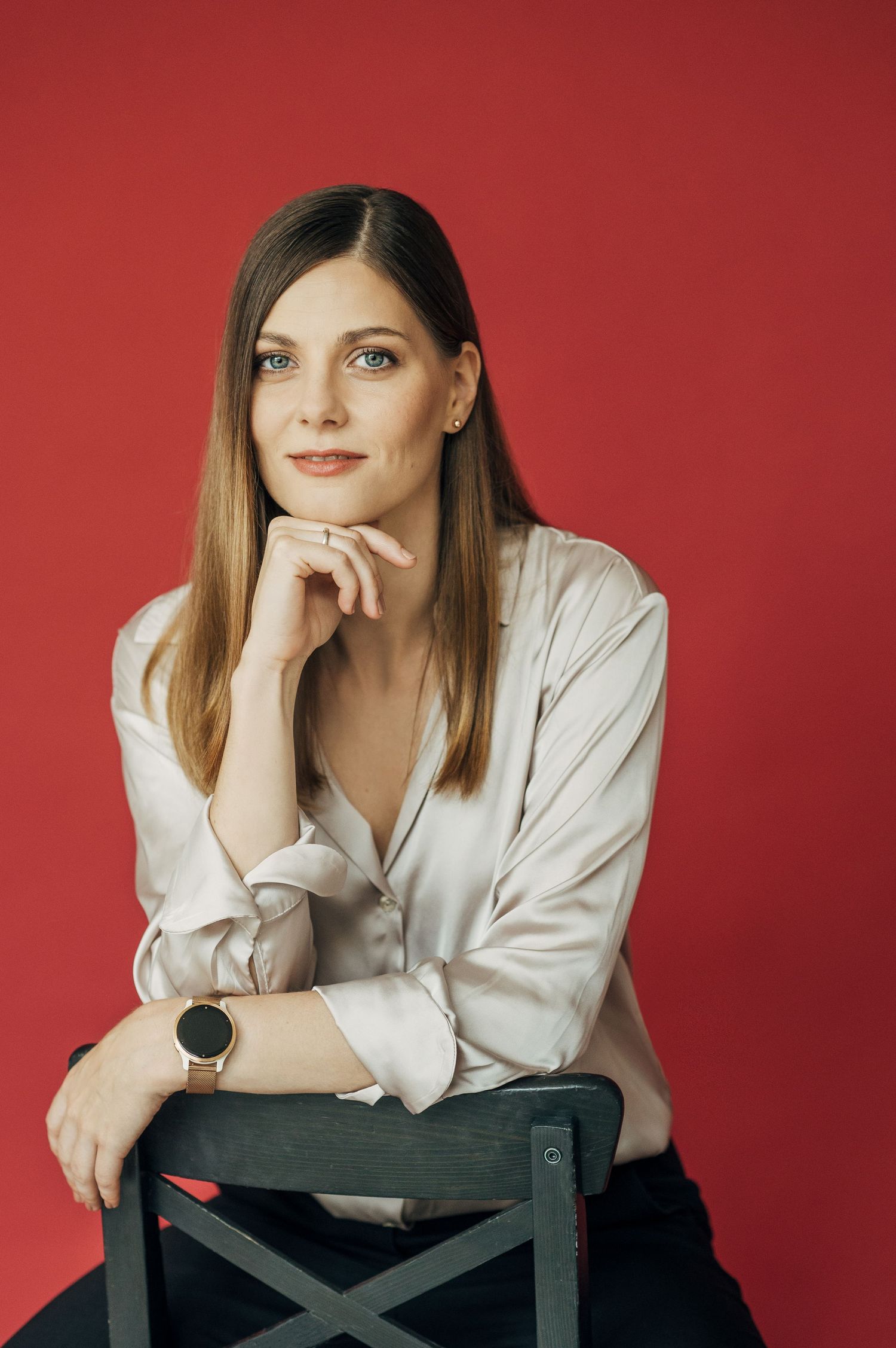 Creative portraits of a person leaning on a chair against red background wearing light colored clothing.