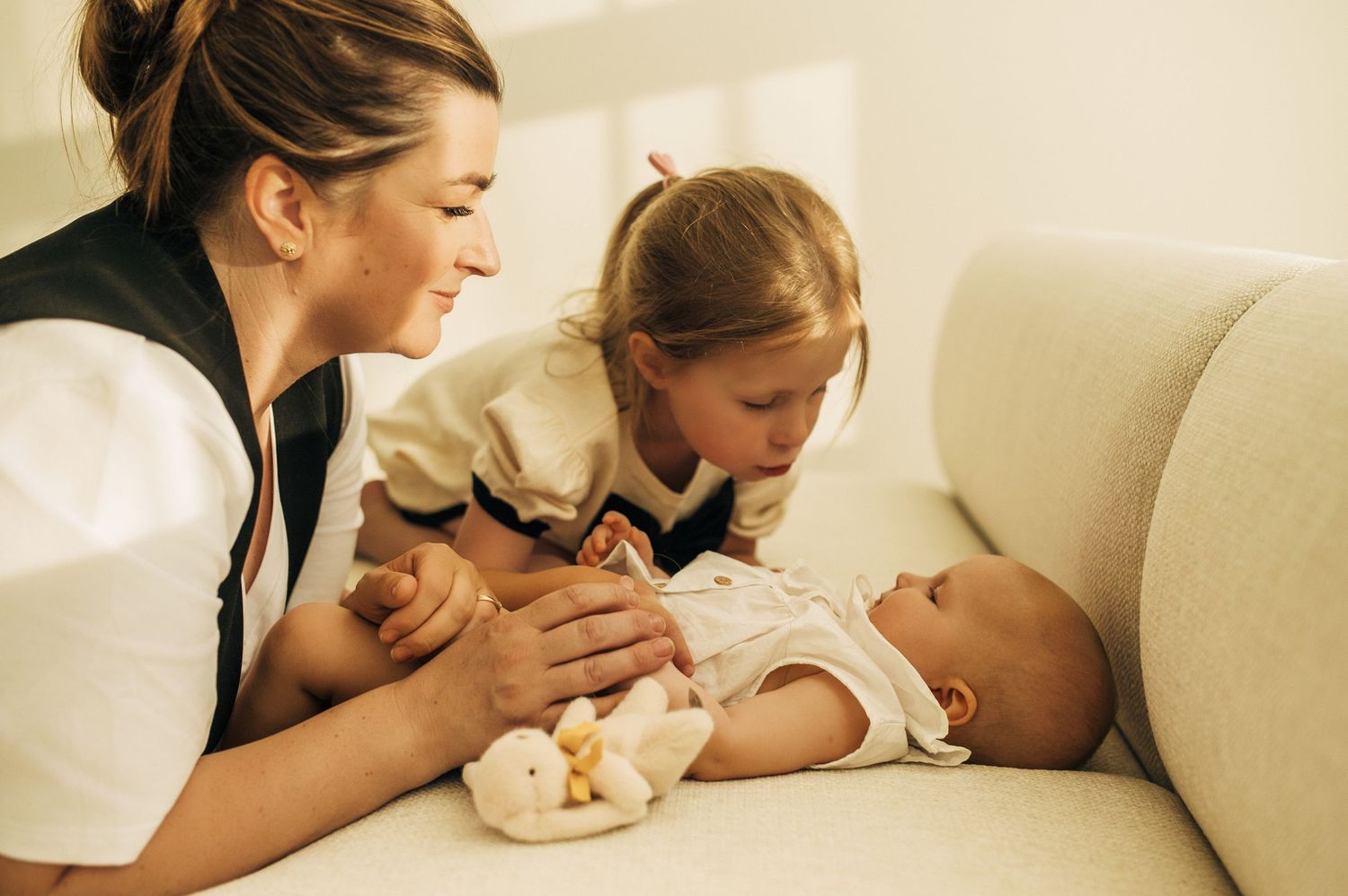 A tender family moment with a baby on a white couch.