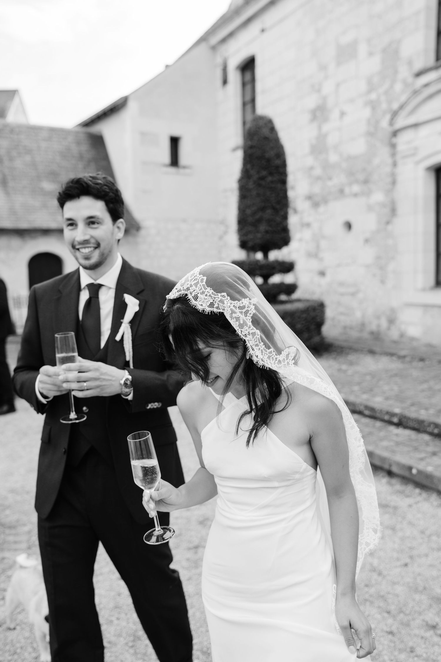 Photo du mariage premium à Angers avec les mariés pendant le cocktail et une coupe de champagne. Photo en noir et blanc et en mouvement.