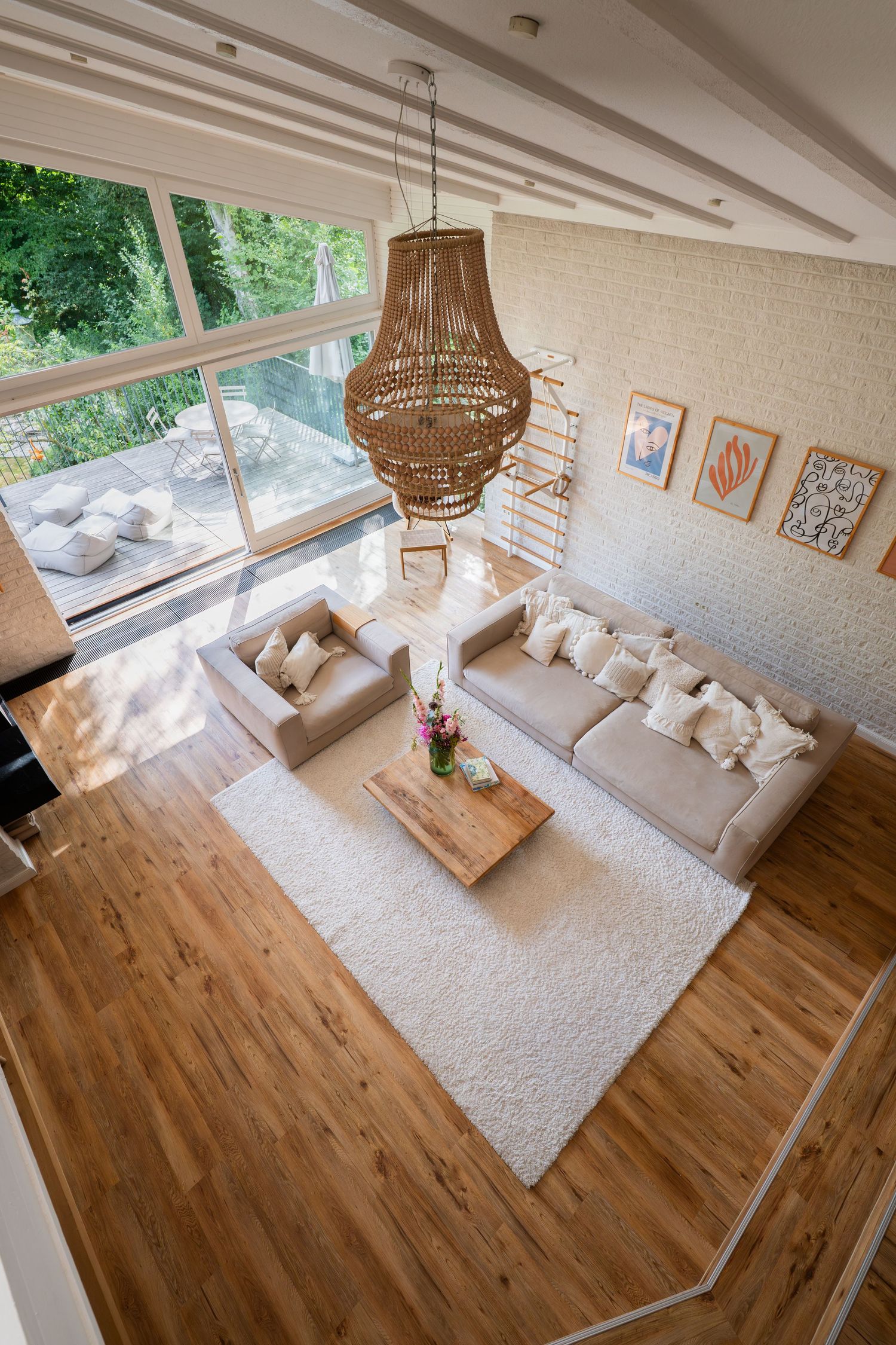 Bright living room with hardwood floors, white walls, and a beige area rug under contemporary furniture.