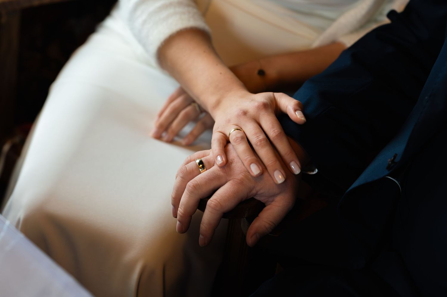 Close-up of hands holding a white pen while writing or signing documents on a desk.