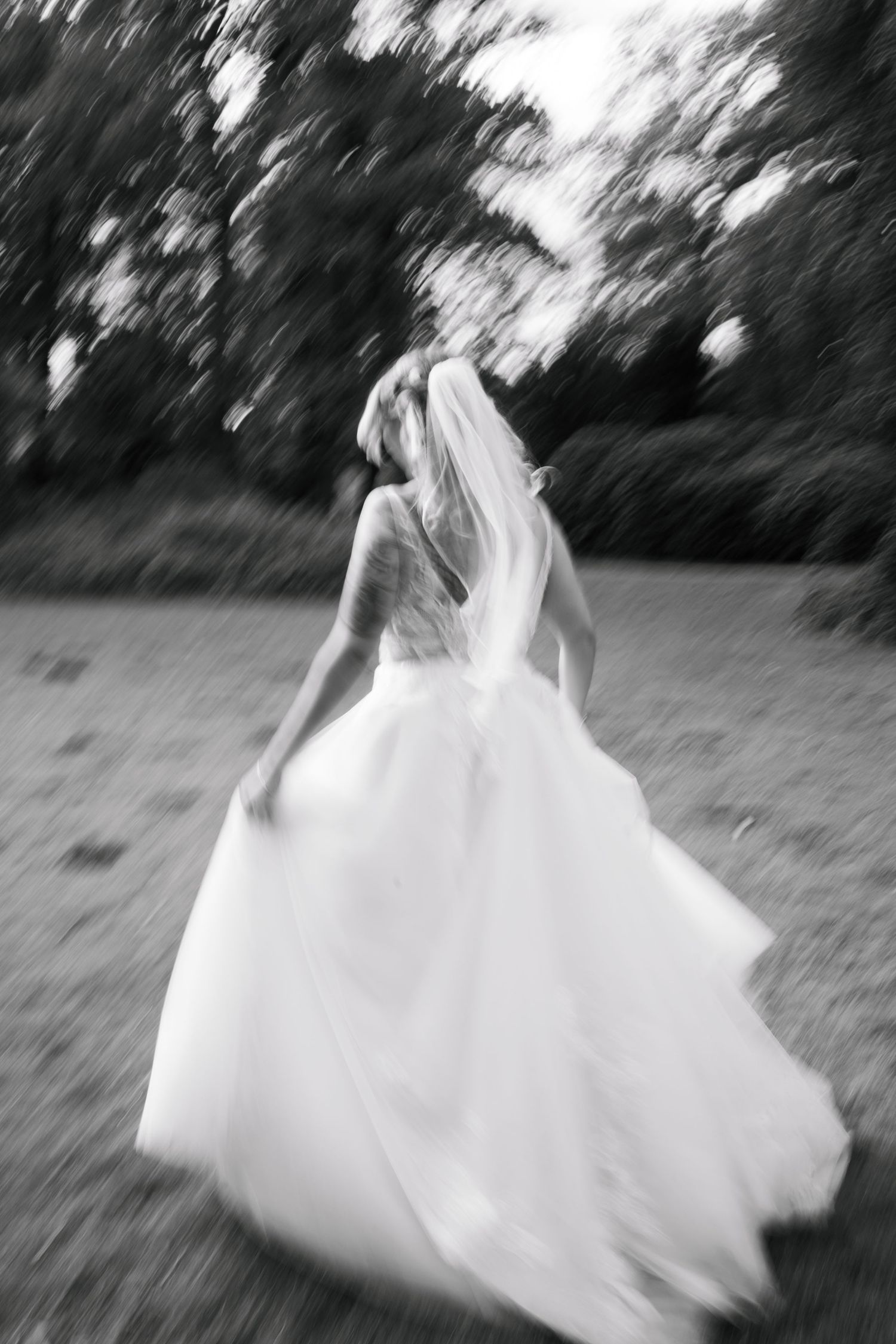 A series of motion-blurred black and white photographs showing someone in a flowing white dress spinning in a field.