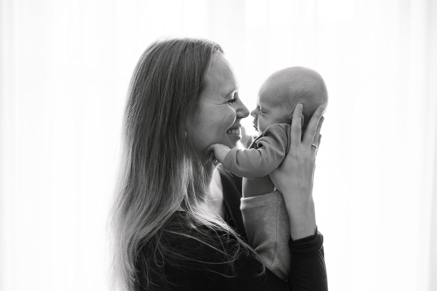 A tender black and white portrait of a parent sharing an intimate moment with their baby.
