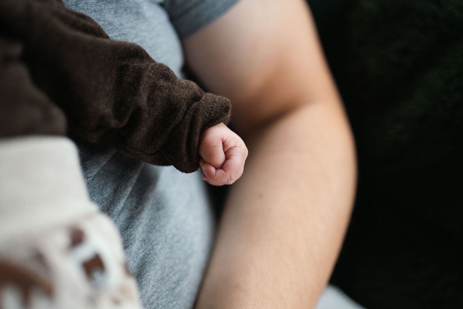 A close-up view of hands holding a tiny baby's feet in a gentle, nurturing moment.