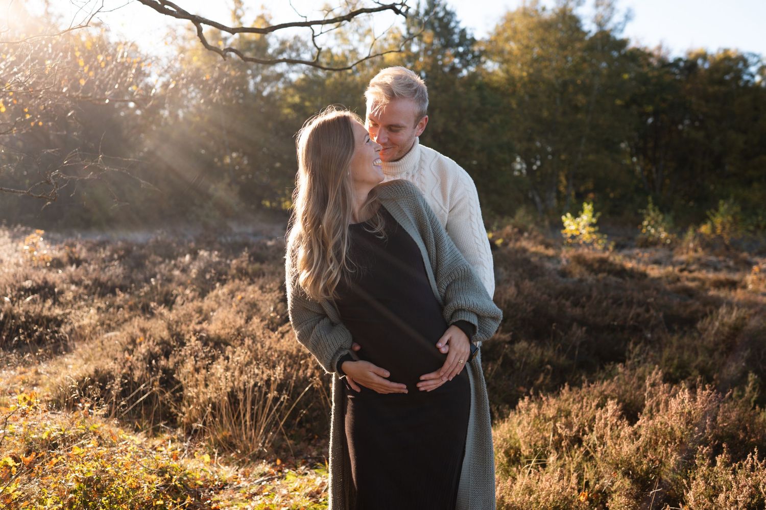 A couple embraces in a romantic moment among blooming heather during golden hour sunset.
