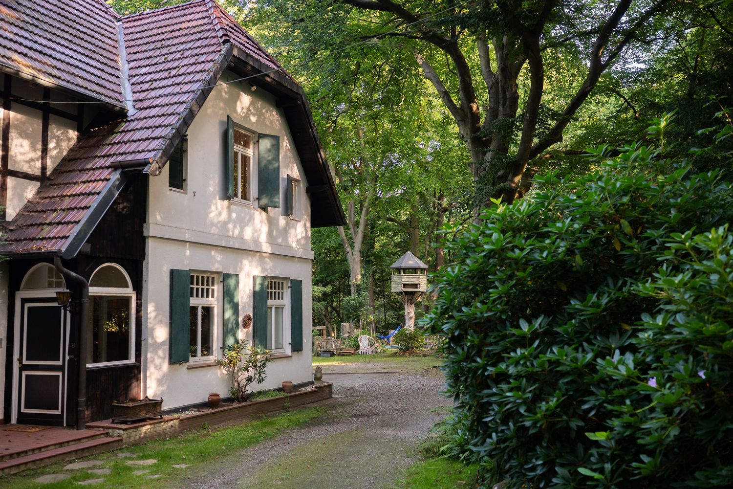 A row of charming cottage-style houses with purple roofs nestled among lush green trees on a peaceful street.