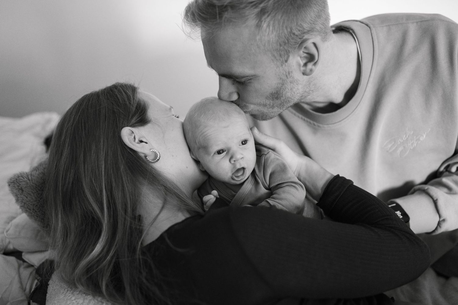 A collection of intimate black and white photographs showing tender parent-child bonding moments and embraces.