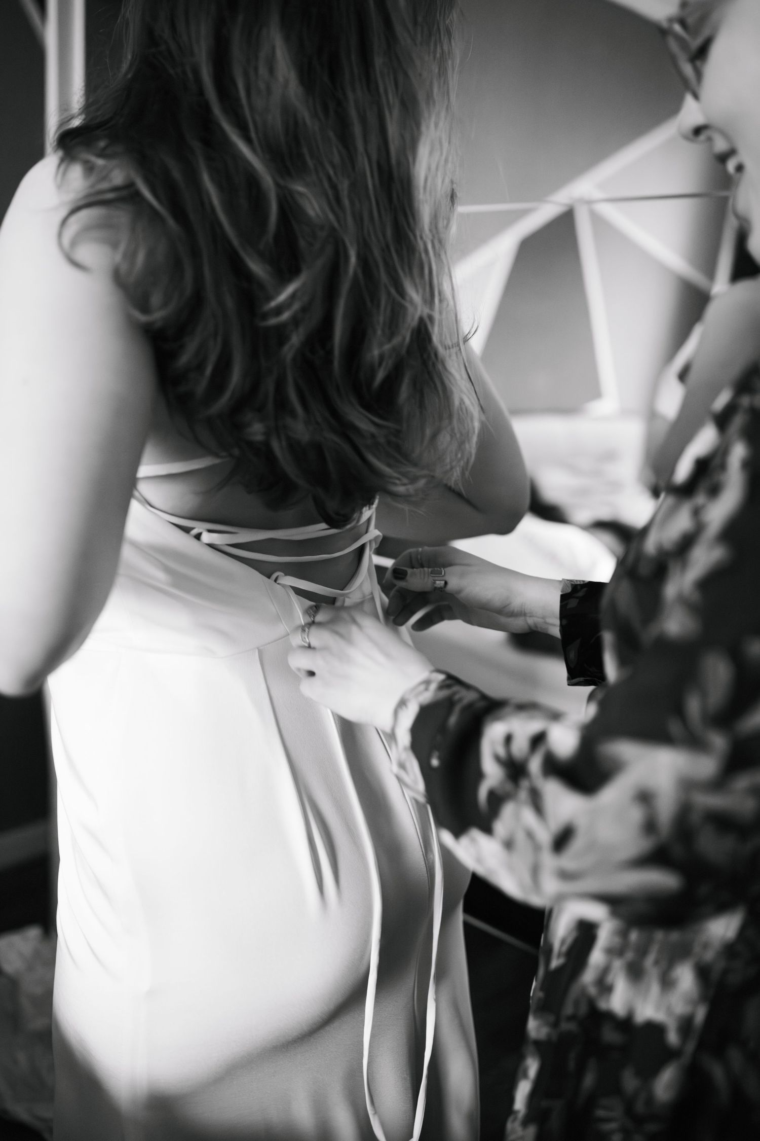 Close-up black and white photos showing details of an elegant white wedding dress with bow accents.