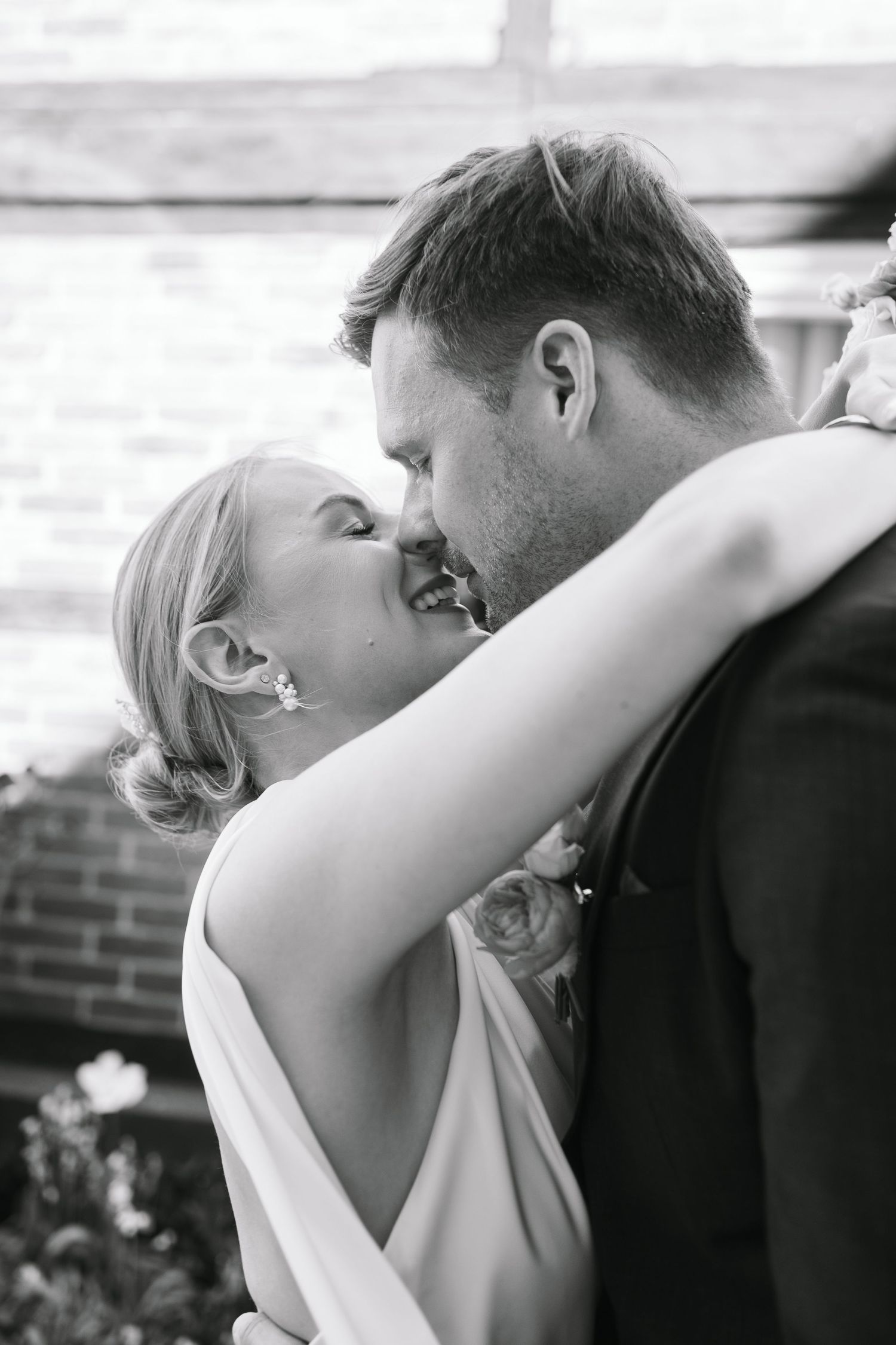 Black and white photo of a bride and groom sharing a romantic kiss on their wedding day.
