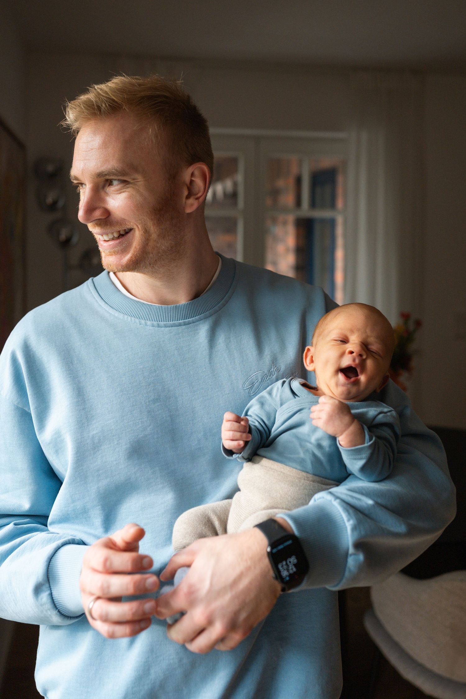A series of candid moments showing a person in a light blue sweater holding and interacting with a laughing baby.