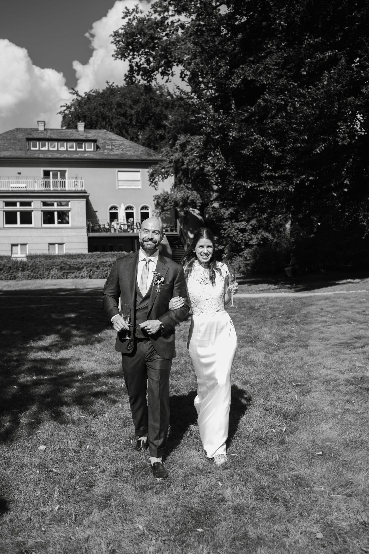 Black and white sequence of a couple walking together on grass with a building in the background.