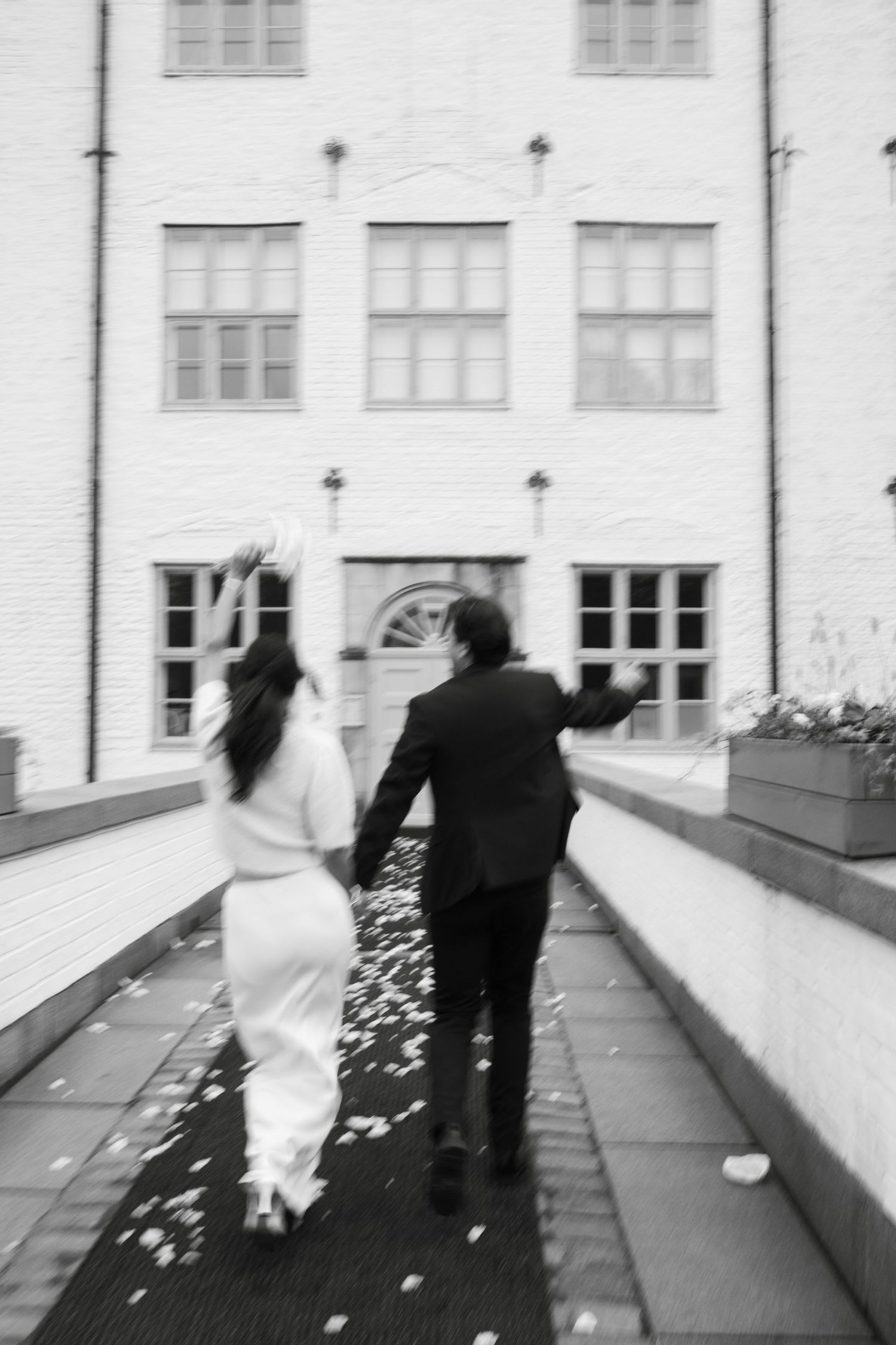 A sequence of black and white photos showing a couple in wedding attire walking along a building ledge.