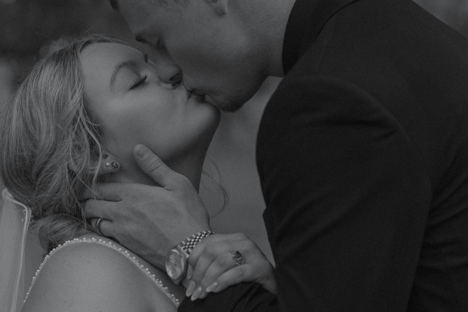 Black and white close-up of a bride and groom sharing a romantic kiss on their wedding day.