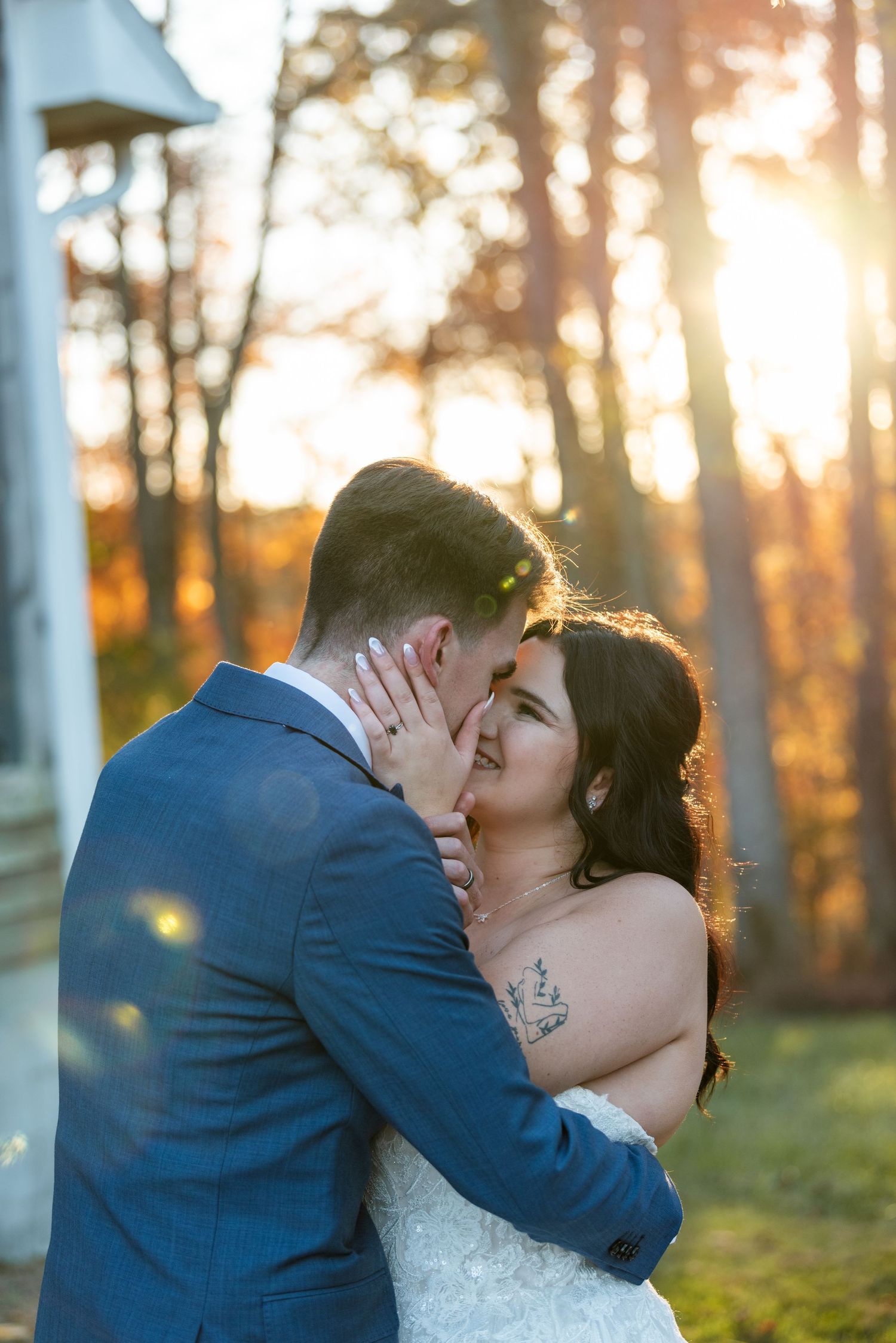 Bride and groom sharing a romantic kiss at golden hour sunset in an autumn forest wedding portrait.