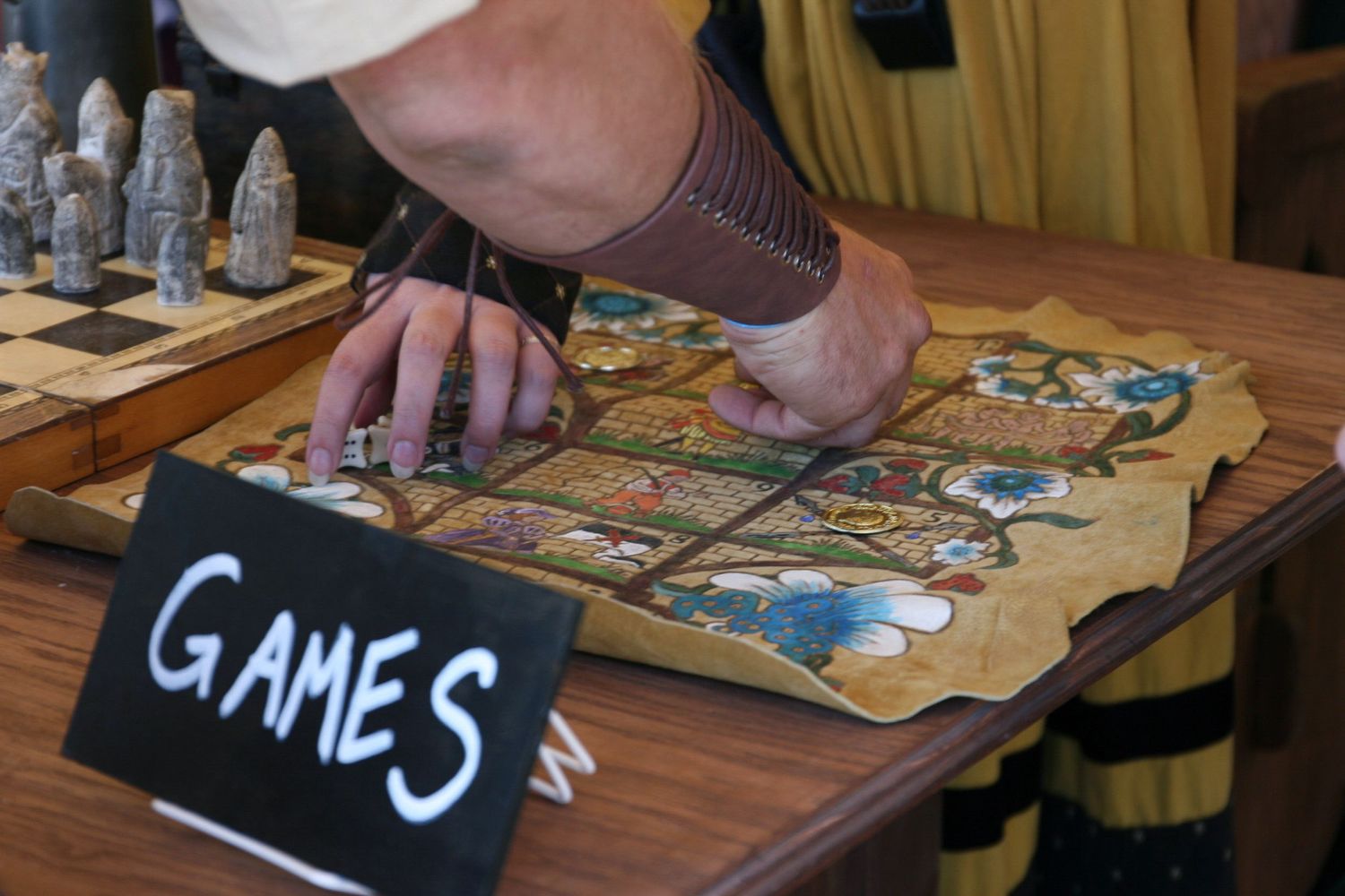 Two patrons play a game of Gluckhaus, a gambling game, in a tent. The game board was handcrafted by one of fair-goer Nicole Graeler’s friend