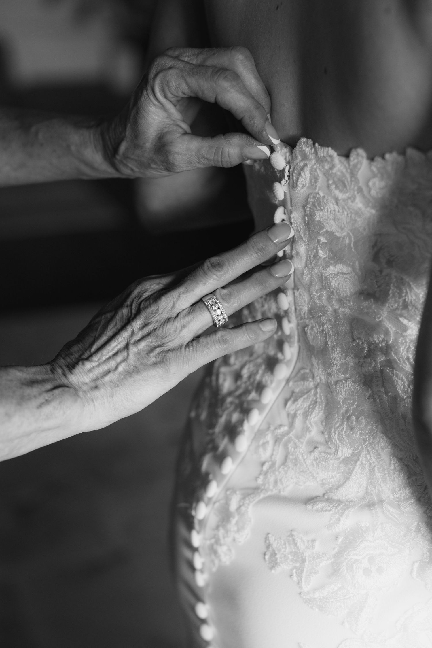 Close-up details of delicate lace and buttons on the back of an elegant white wedding dress.