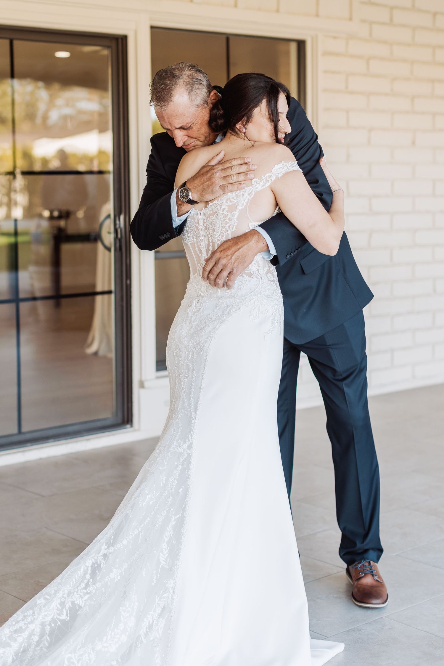 A series of intimate wedding photos showing tender embraces between the couple in formal attire against a light brick wall.