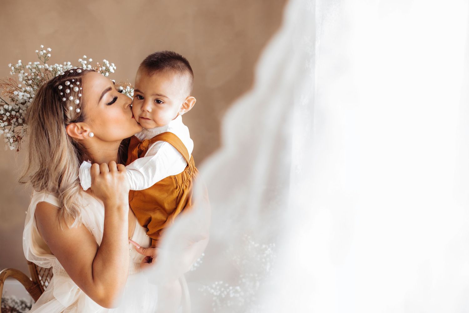 Angelic bride in white gown surrounded by light delicate feathers creating an ethereal wedding photography scene.