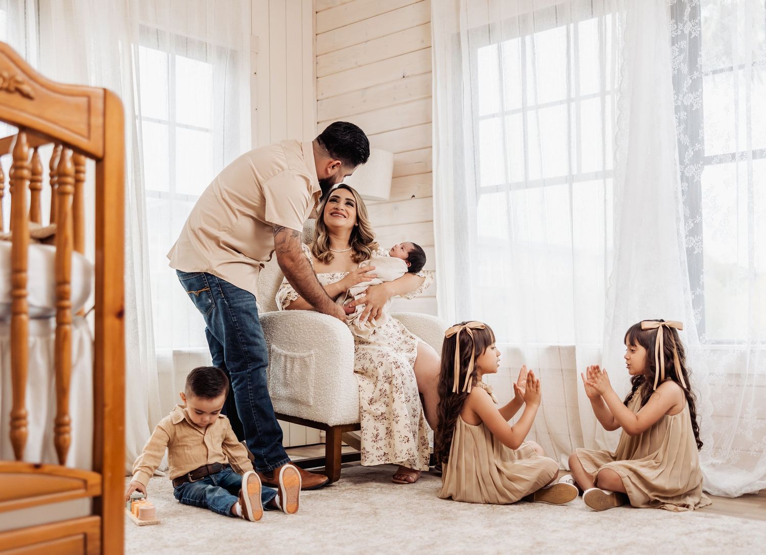 A group gathers in a bright white room with wooden floors and stairs, creating a warm and intimate atmosphere.