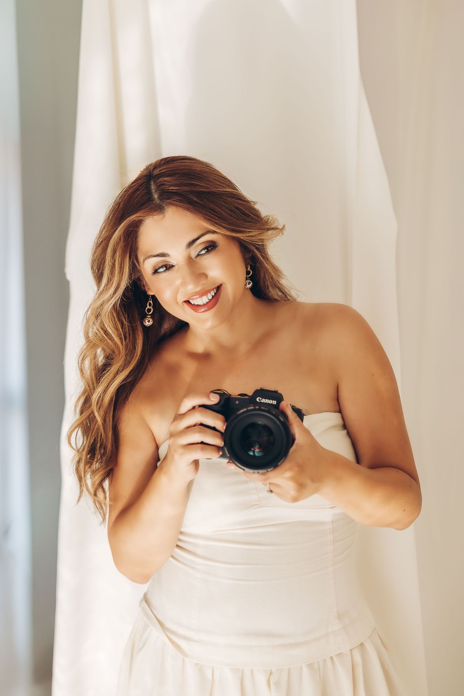 Woman in white strapless dress poses with camera against light backdrop in photo series.