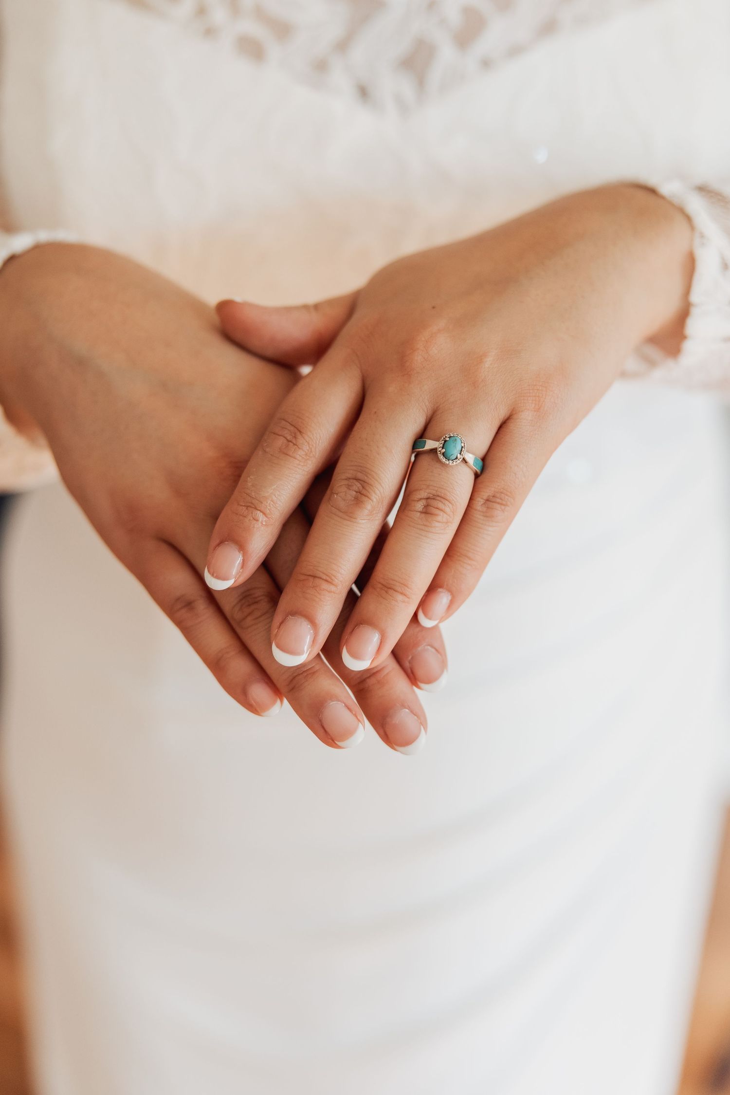Close-up series of hands displaying an engagement ring against a white fabric background.