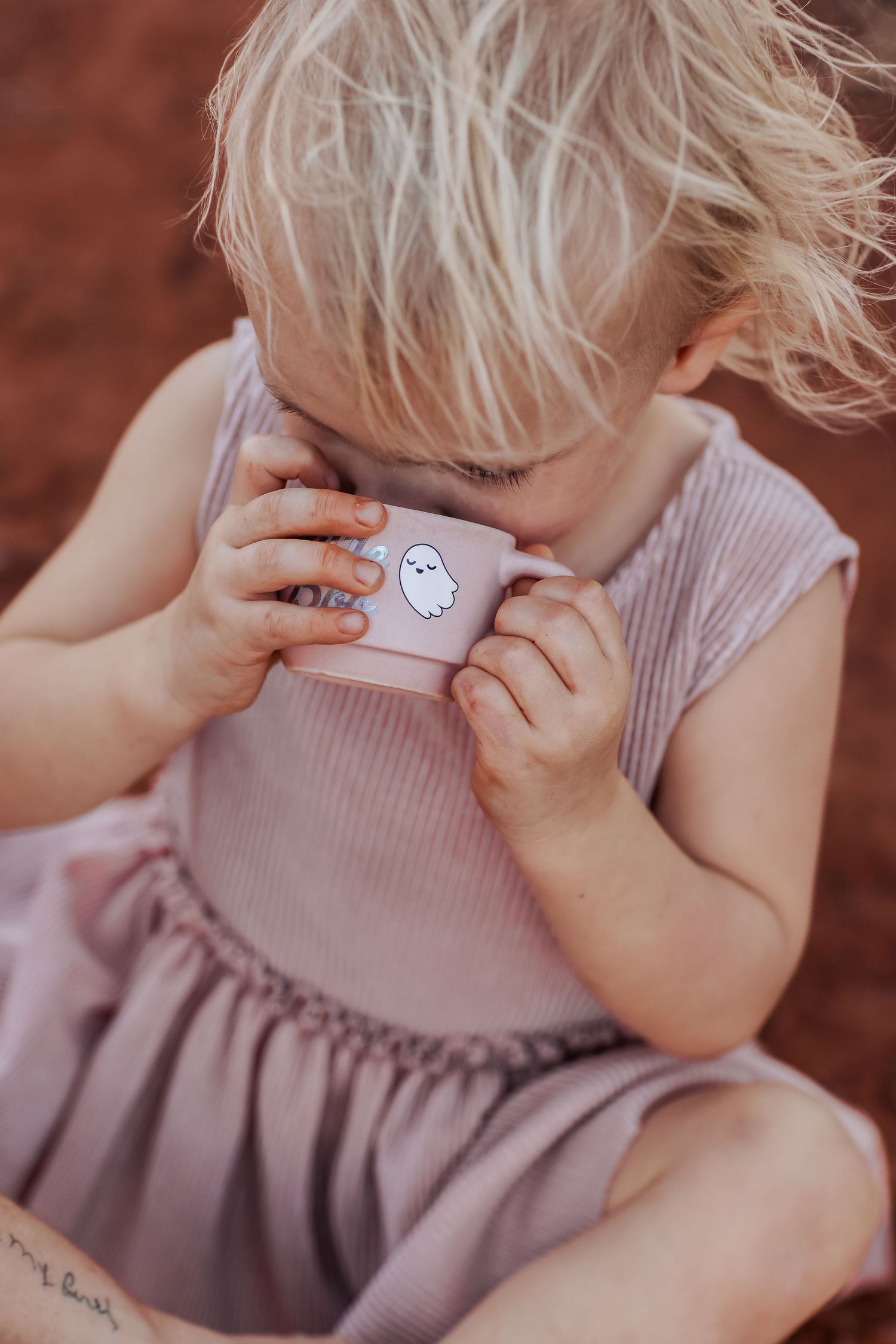 A child in a pink dress plays with a small ghost-themed toy in a series of sequential photos.