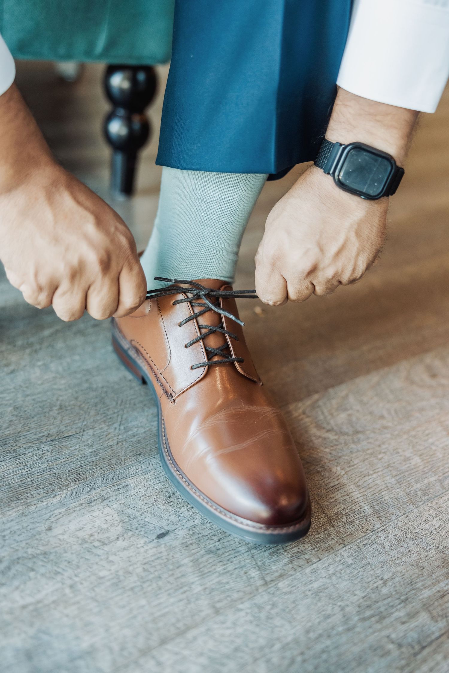 Close-up sequence showing brown leather dress shoes being laced up on a gray floor.