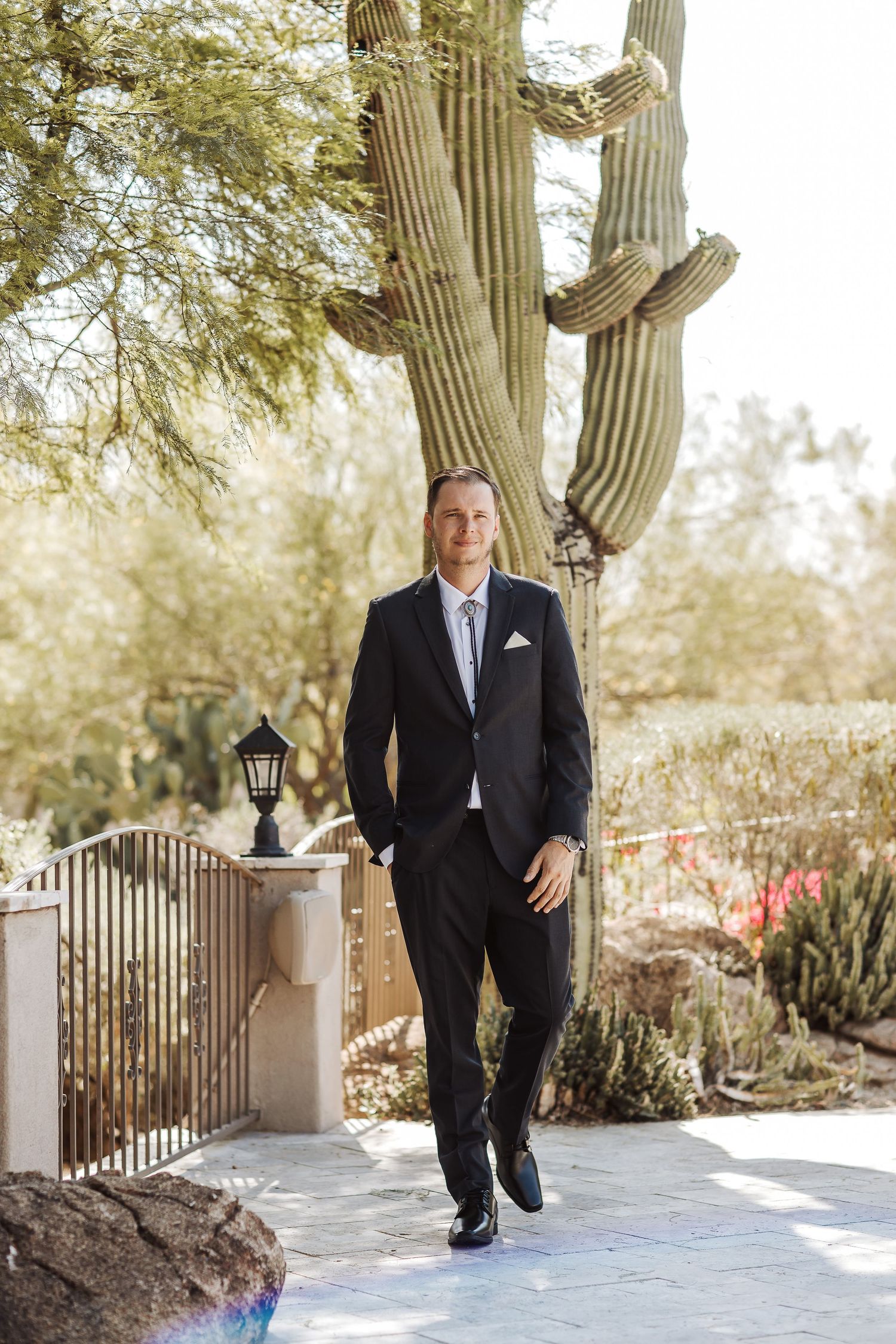 Elegant formal attire photographed in front of a towering saguaro cactus on a sunny desert walkway.
