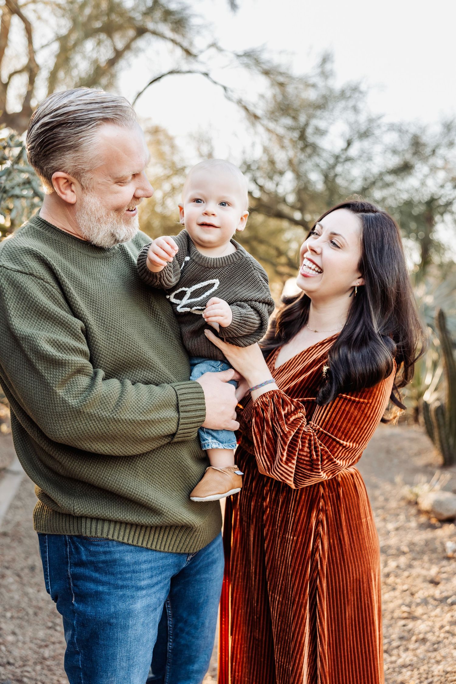 A family shares a joyful moment together outdoors among trees on an autumn afternoon.