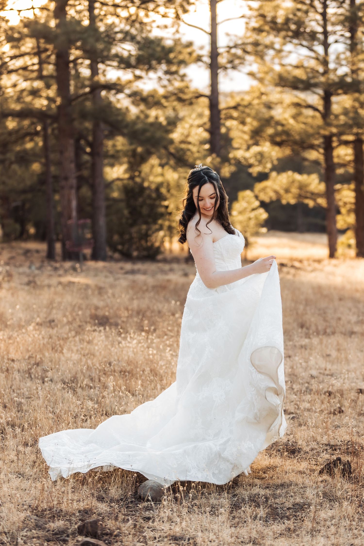 A flowing white wedding dress twirls gracefully in a golden-lit forest setting during sunset.