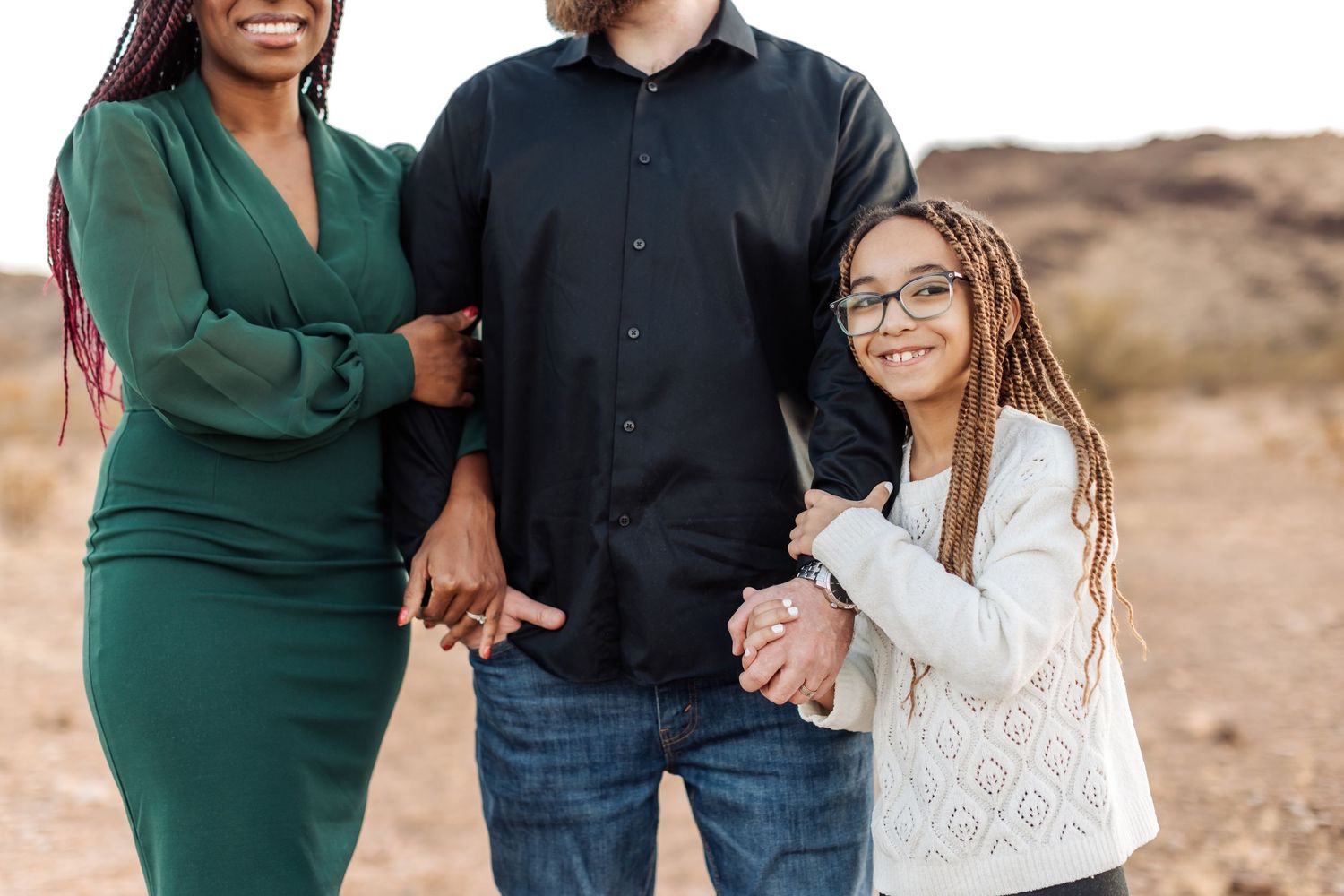 A casual outdoor photo shoot in a desert setting with people wearing coordinated green and black outfits.