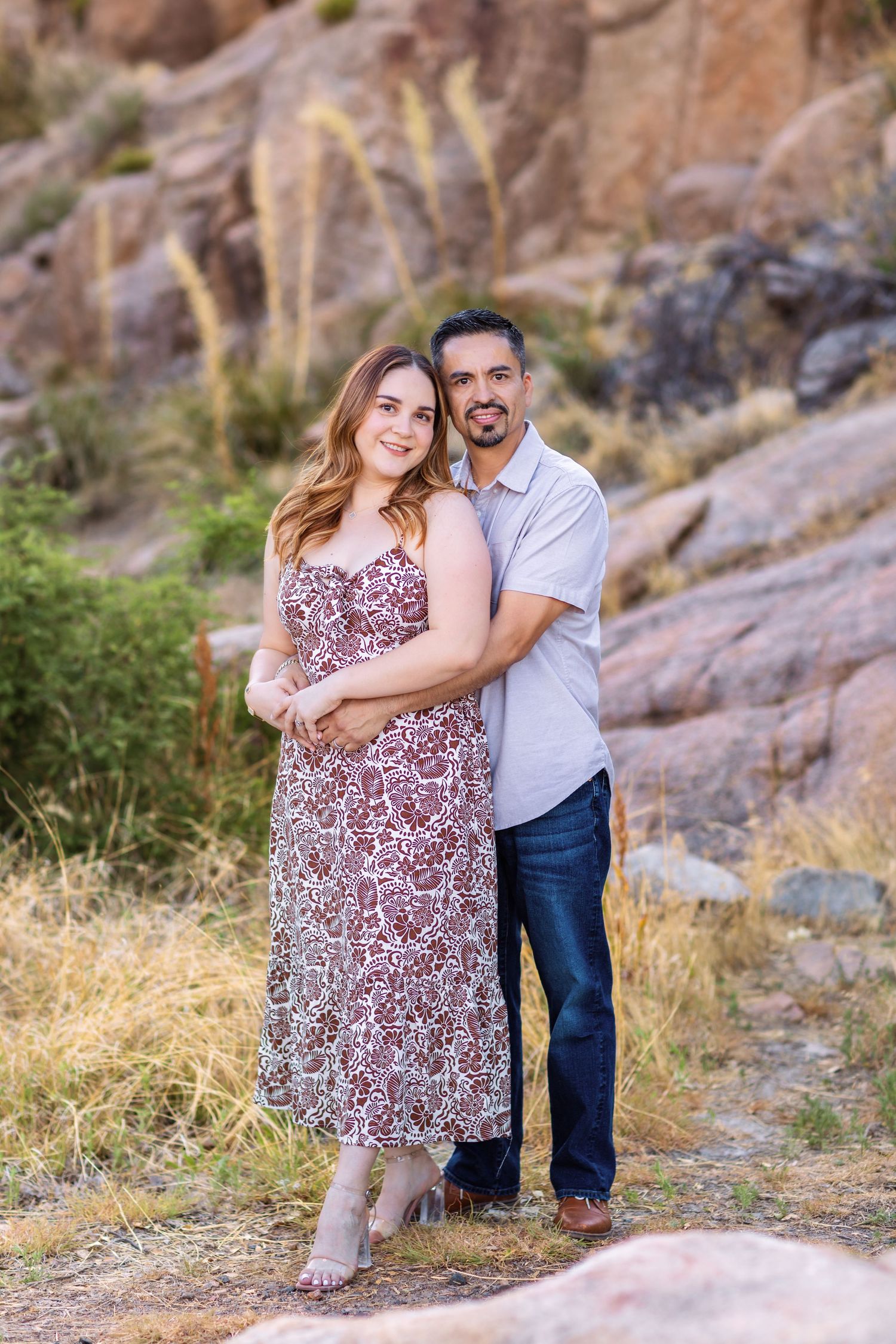 Couple posing together against rocky mountain backdrop during scenic outdoor photo session.