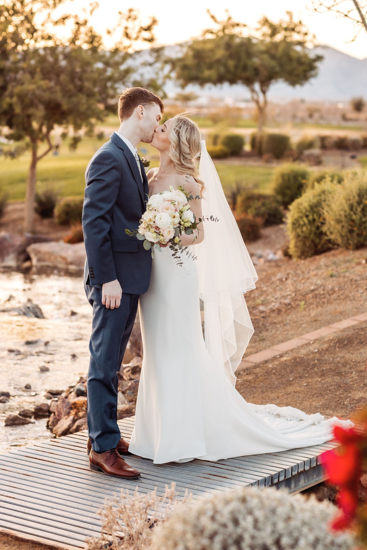 Romantic wedding couple sharing intimate moments on a wooden deck during sunset.