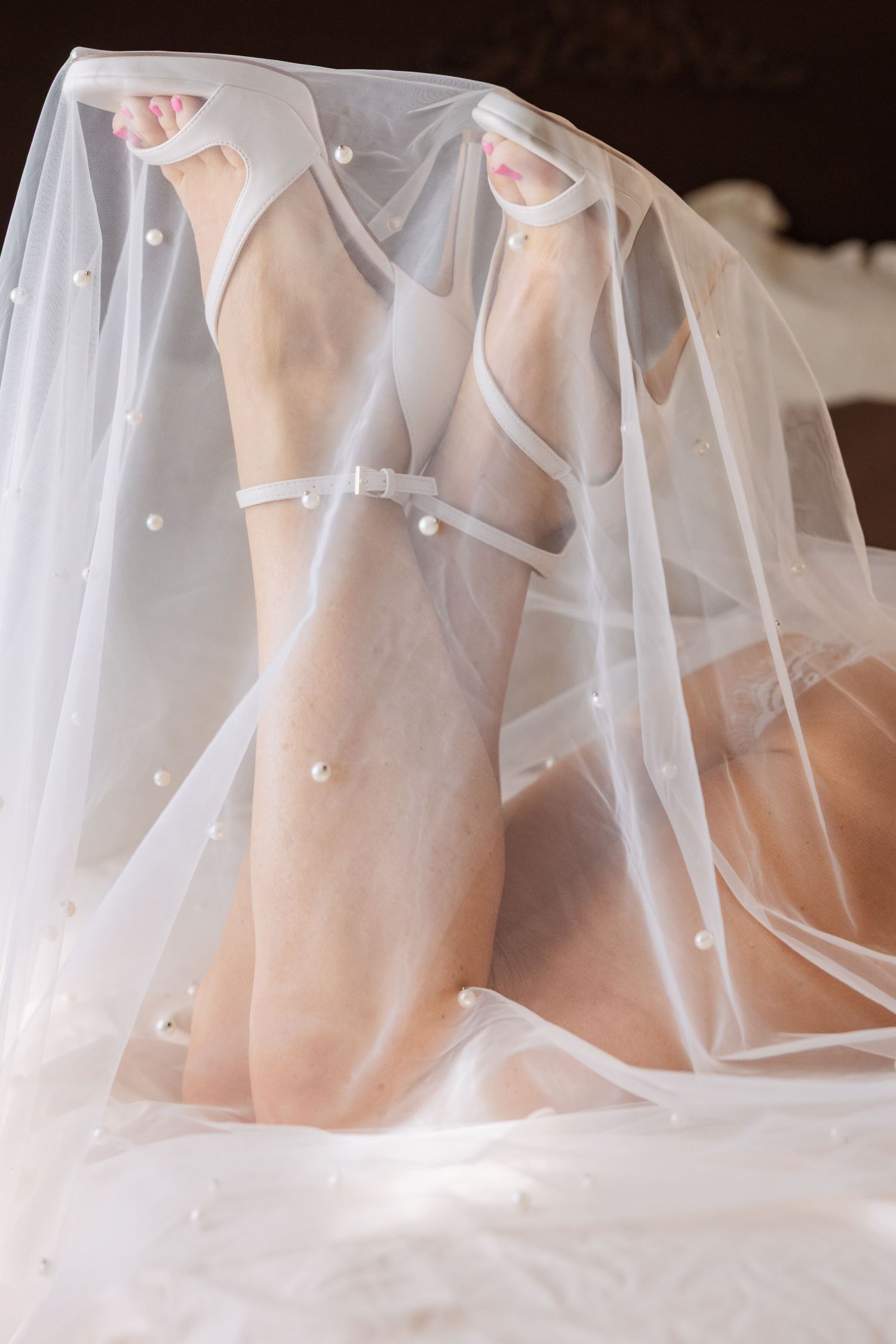 A delicate white tulle bridal veil with scattered pearl embellishments draped elegantly against a light background.