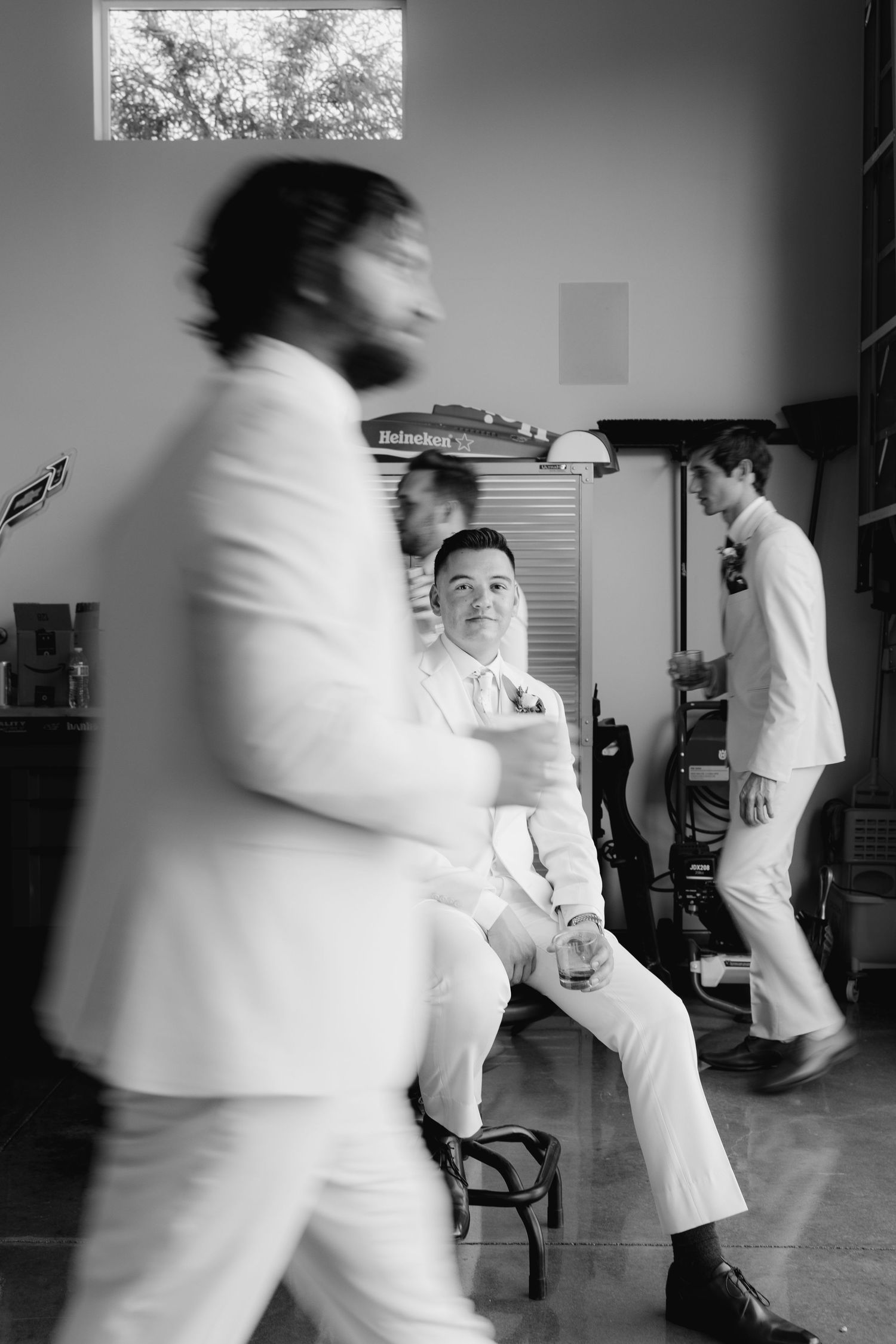 Black and white artistic photograph showing motion blur of people in white suits in an indoor setting.