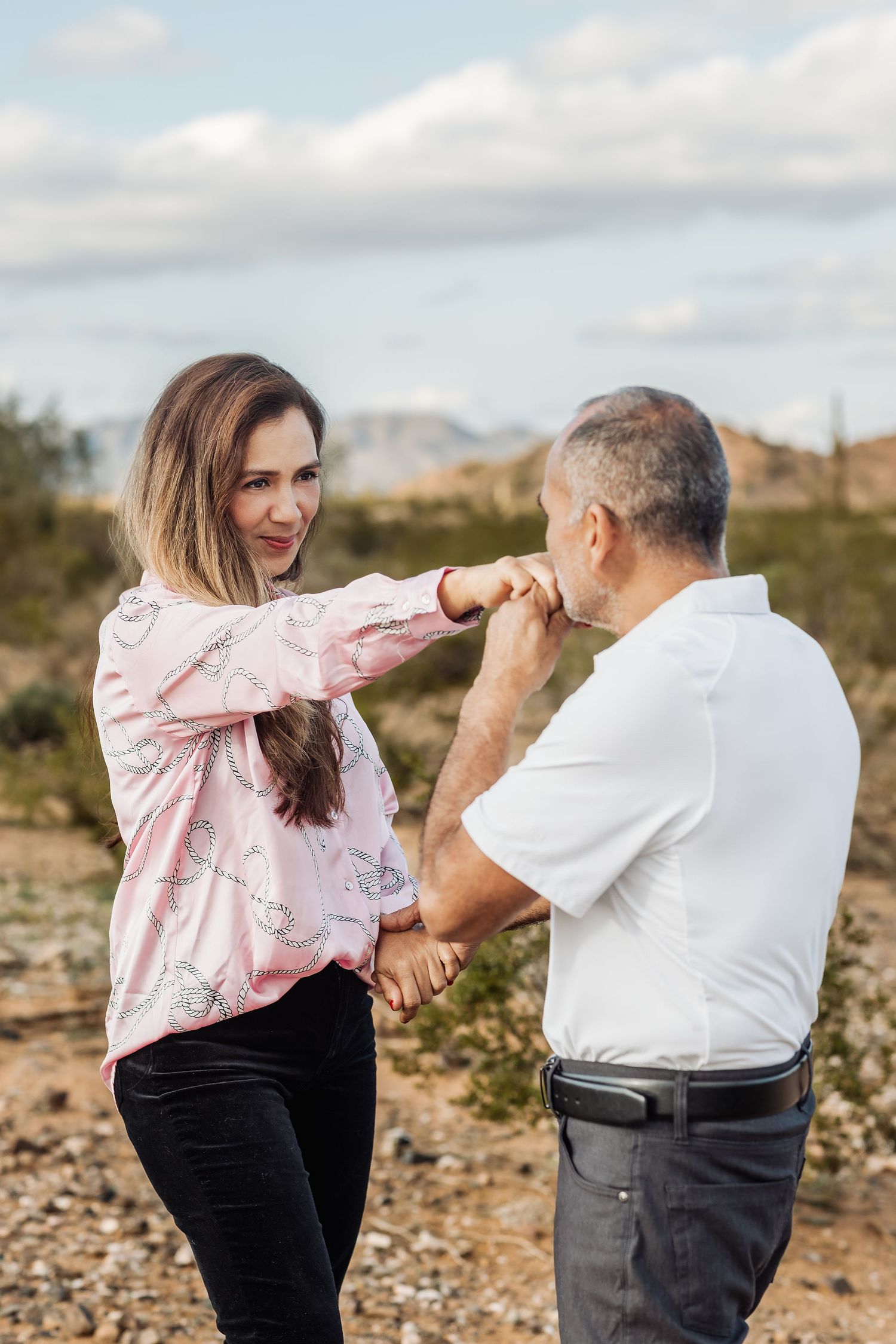 A playful sequence showing a couple in casual attire engaging in a mock boxing match on rocky terrain.