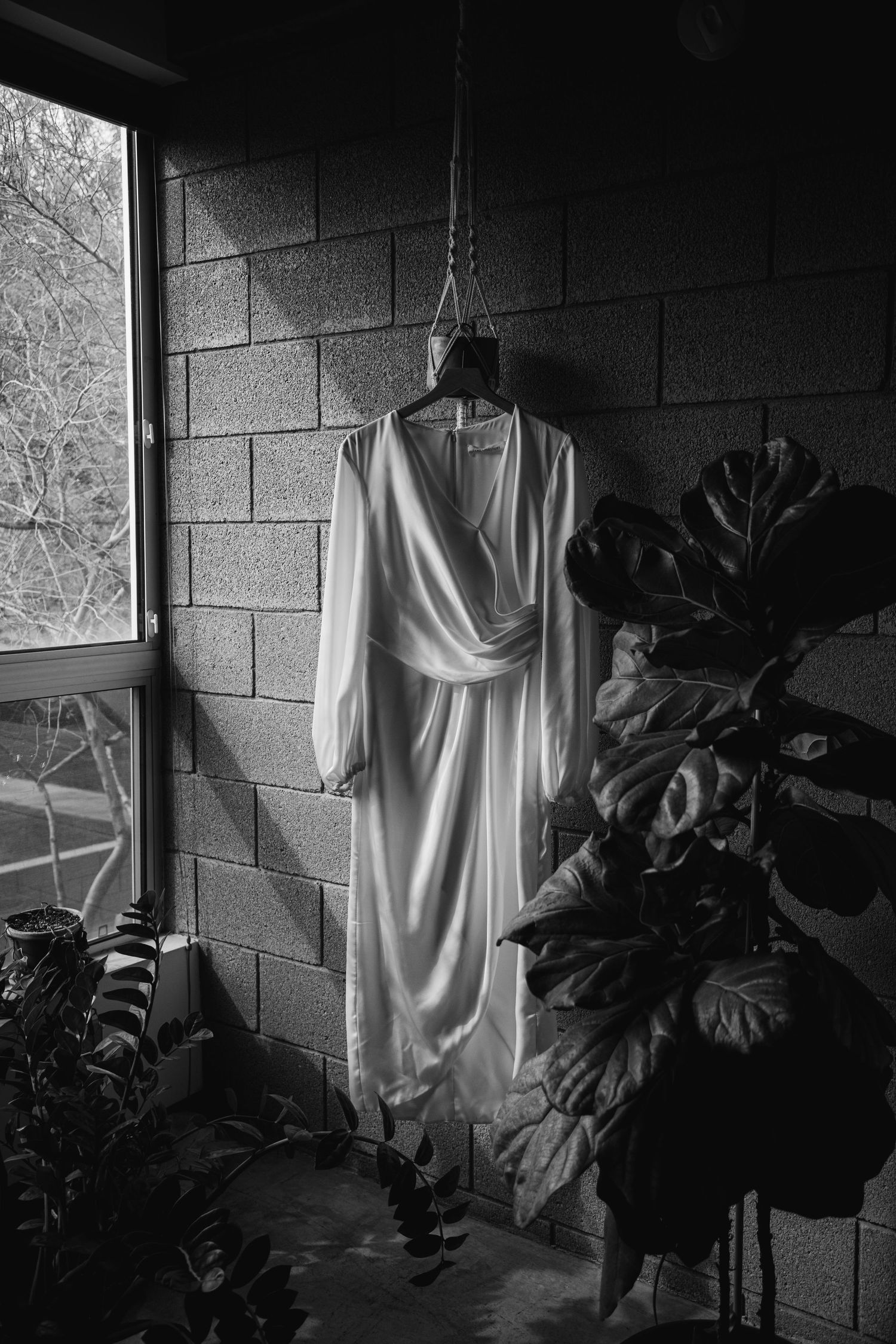 A series of moody black and white photos showing a white dress hanging against concrete walls with dark foliage shadows.
