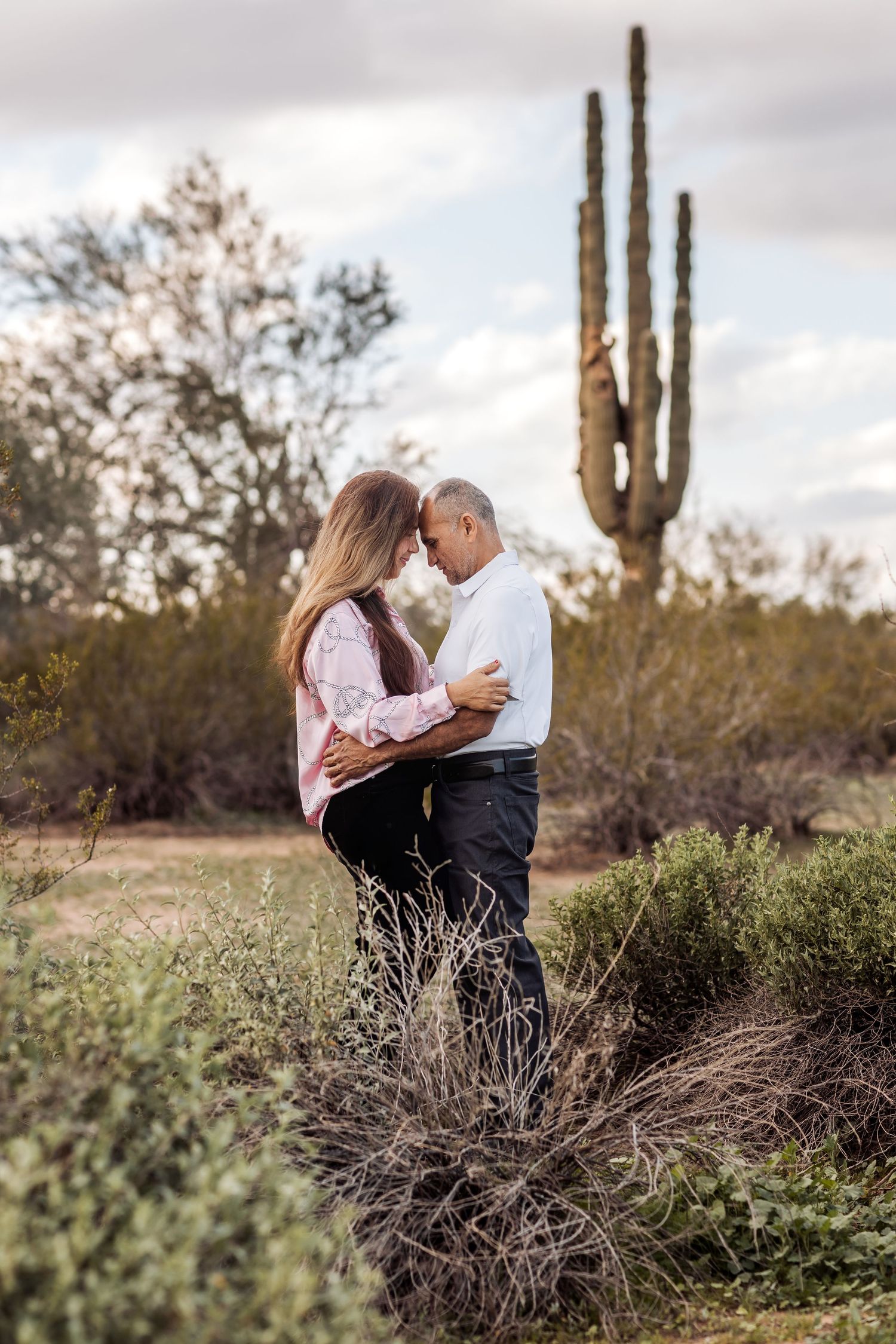 A romantic desert photoshoot with saguaro cacti and desert brush creating a scenic southwestern backdrop.