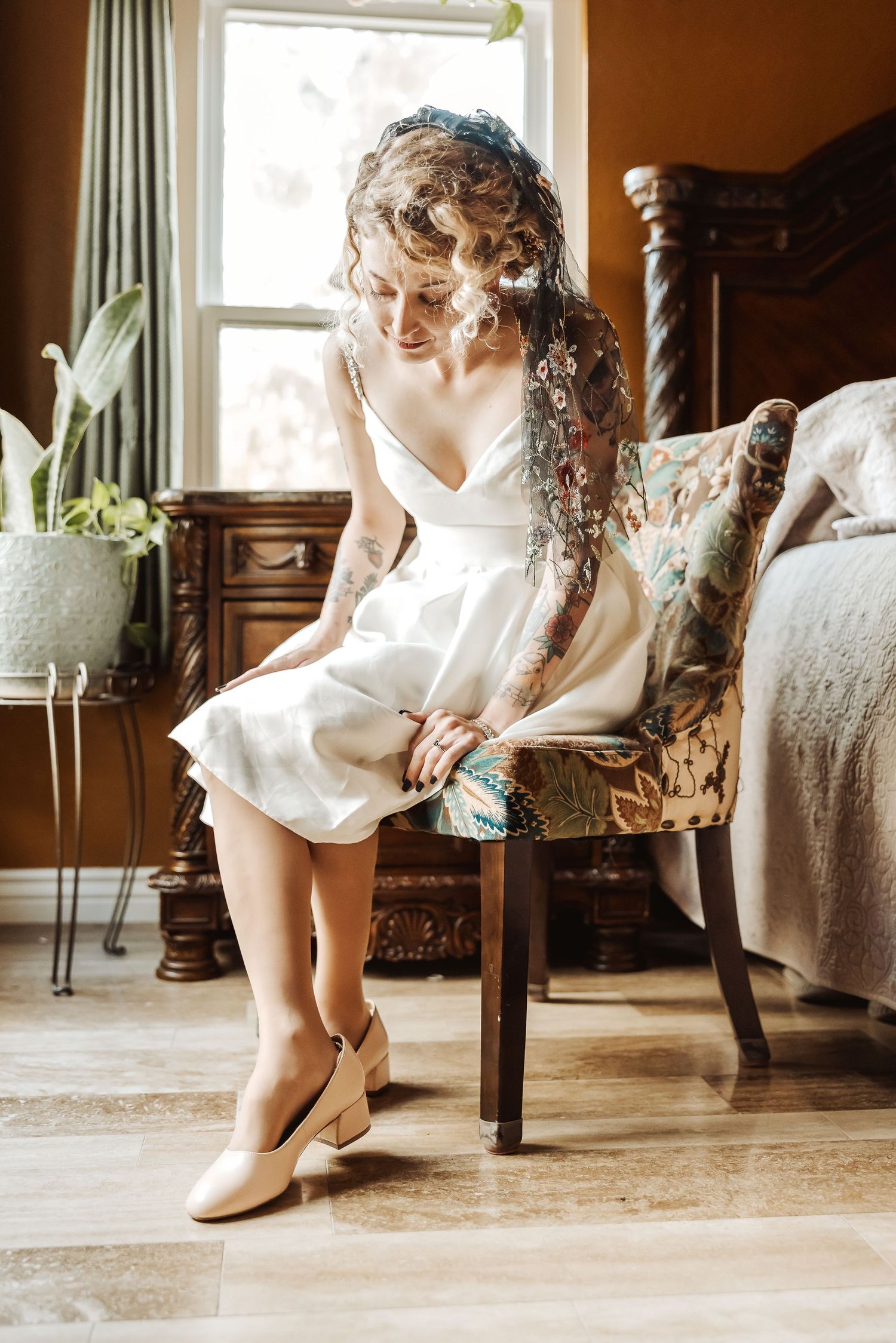 A white short dress and tan shoes shown in an elegant bedroom setting with natural window light.