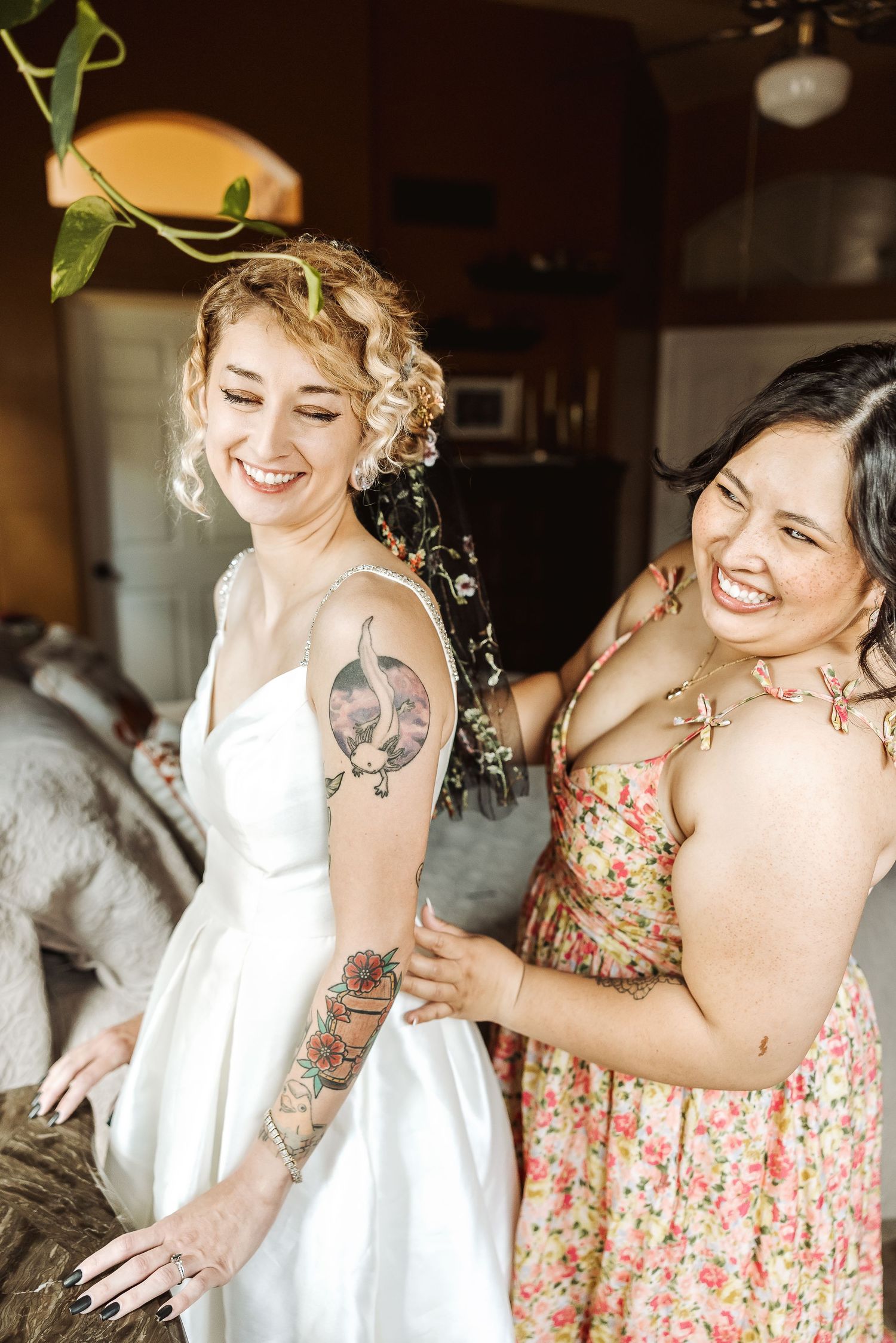 Wedding preparations scene with floral dresses and white gowns in a sunlit room.